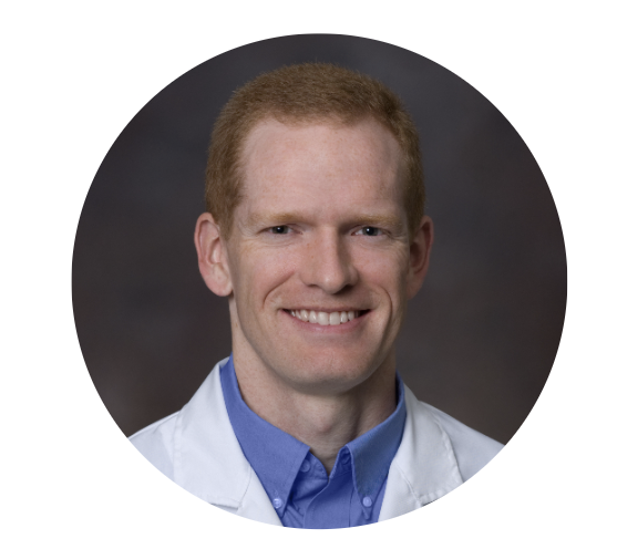 Jeffrey M. Pollock, MD — portrait of a smiling man with red hair wearing a white lab coat and blue collared shirt