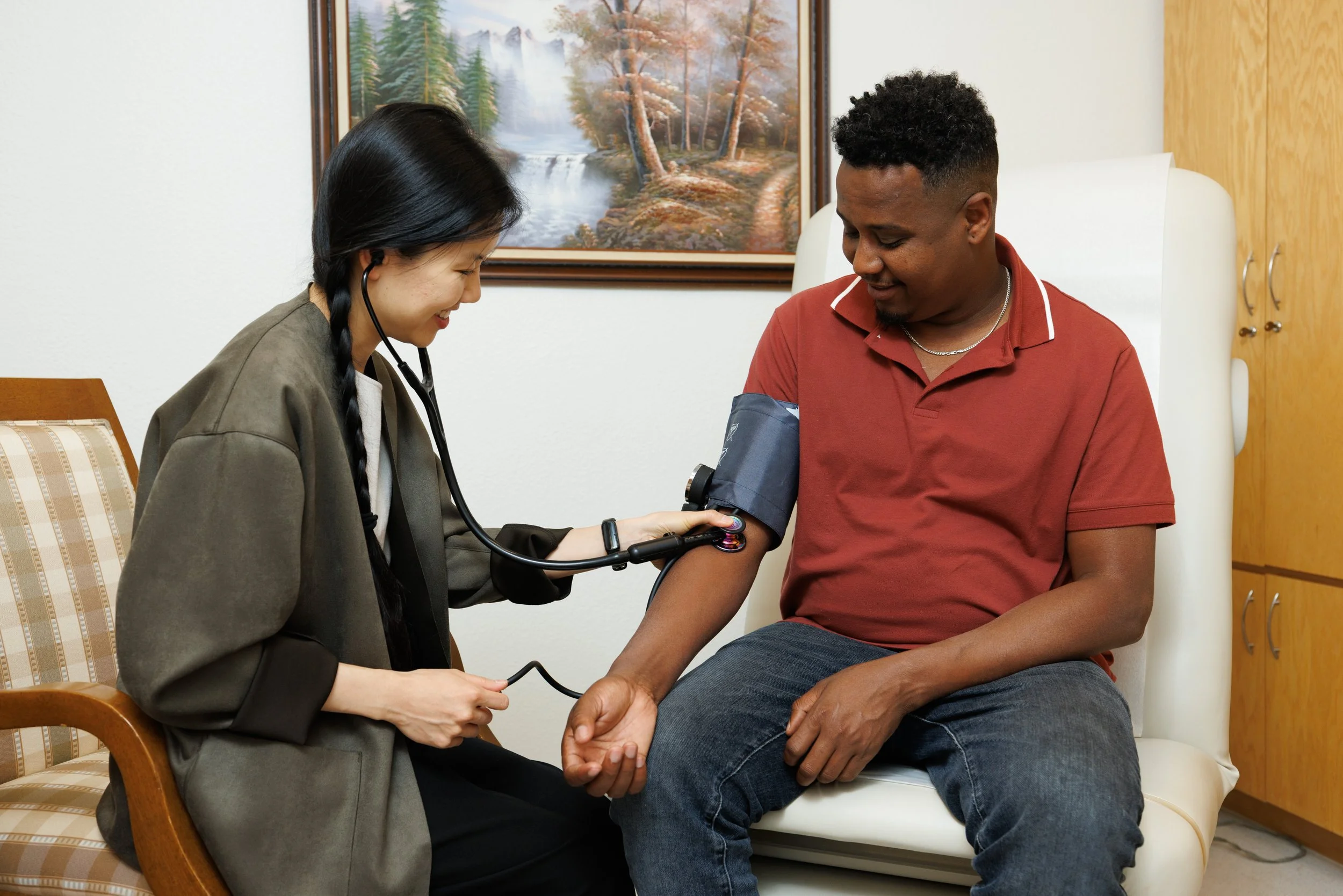 A healthcare professional takes a man's blood pressure using a cuff and sphygmomanometer in a medical setting.