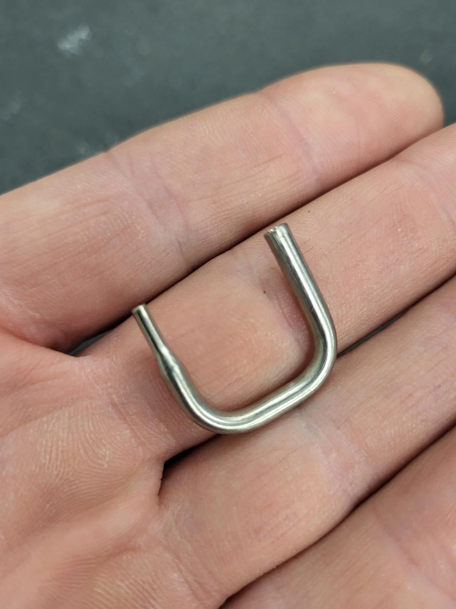A small metal U-shaped object held on a person's hand.