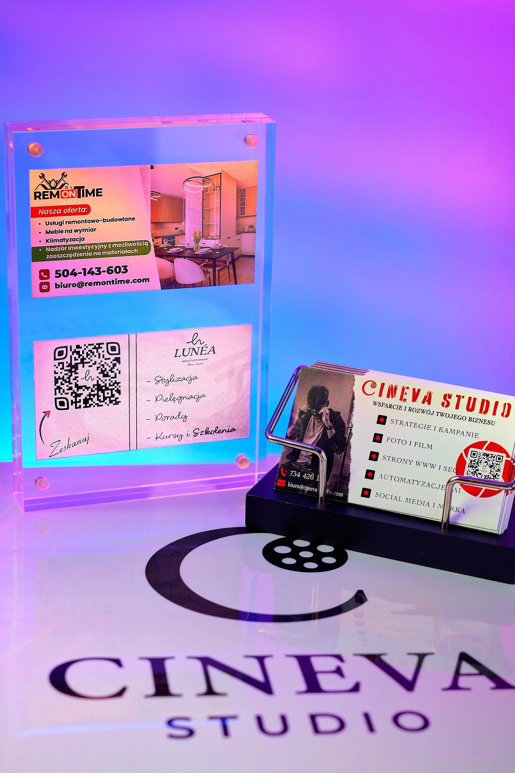 Business cards and advertisements on a table with a CINEVA STUDIO logo projected on the surface, featuring a colorful background with purple and blue hues.