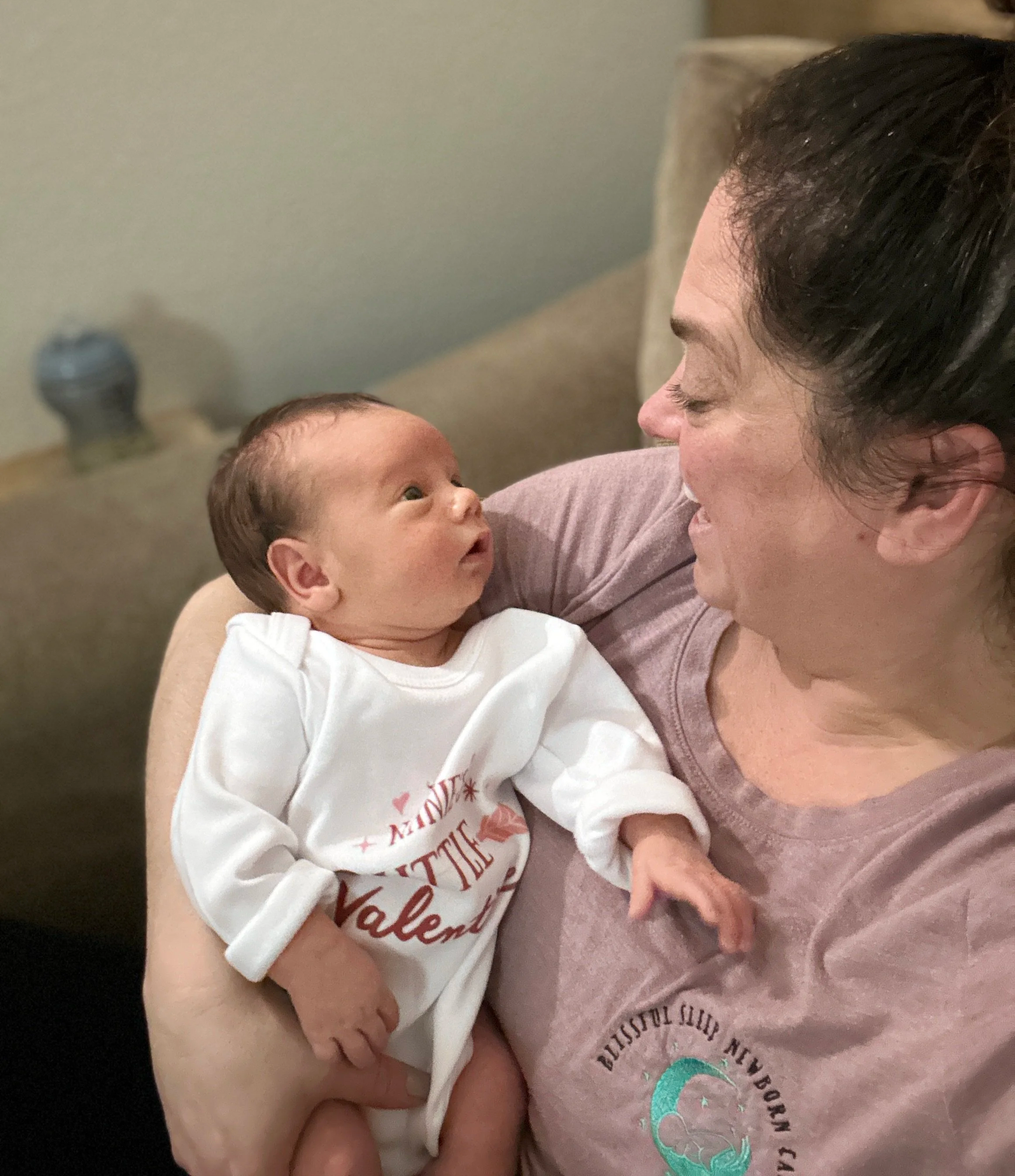 A woman holding a newborn baby, looking into each other's eyes.