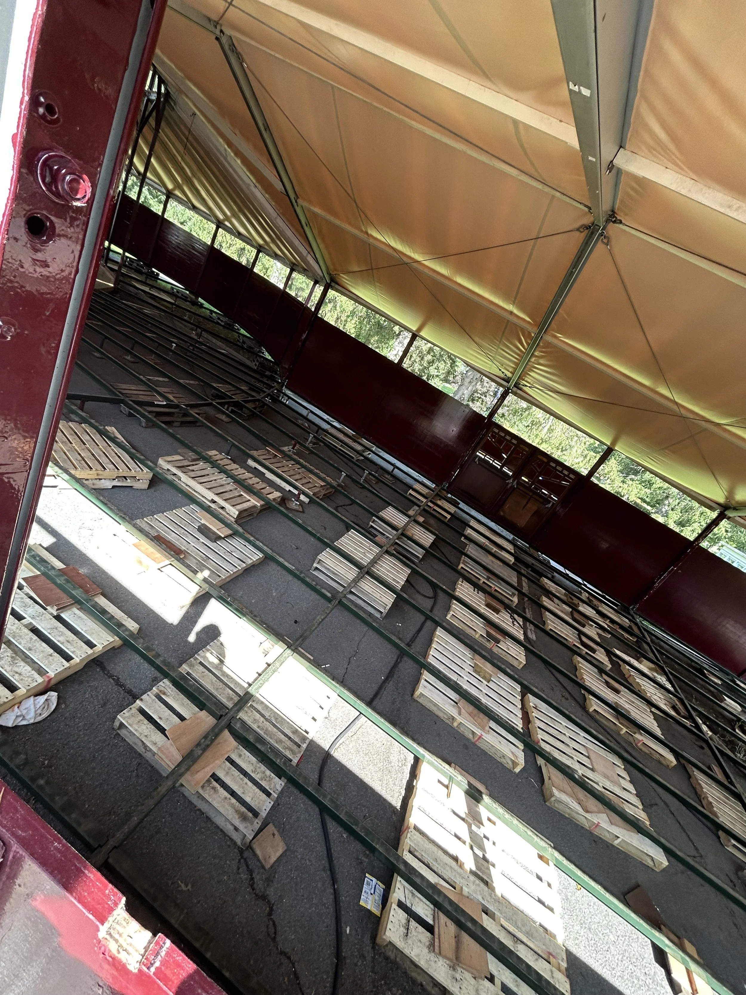 Inside view of a carnival or fair ride tent with empty wooden benches stored on the ground.