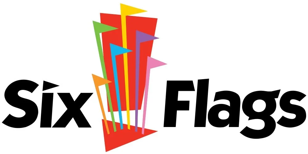 Graphic logo with six colorful flags in red, yellow, green, purple, pink, and blue above black text reading 'Six Flags'.