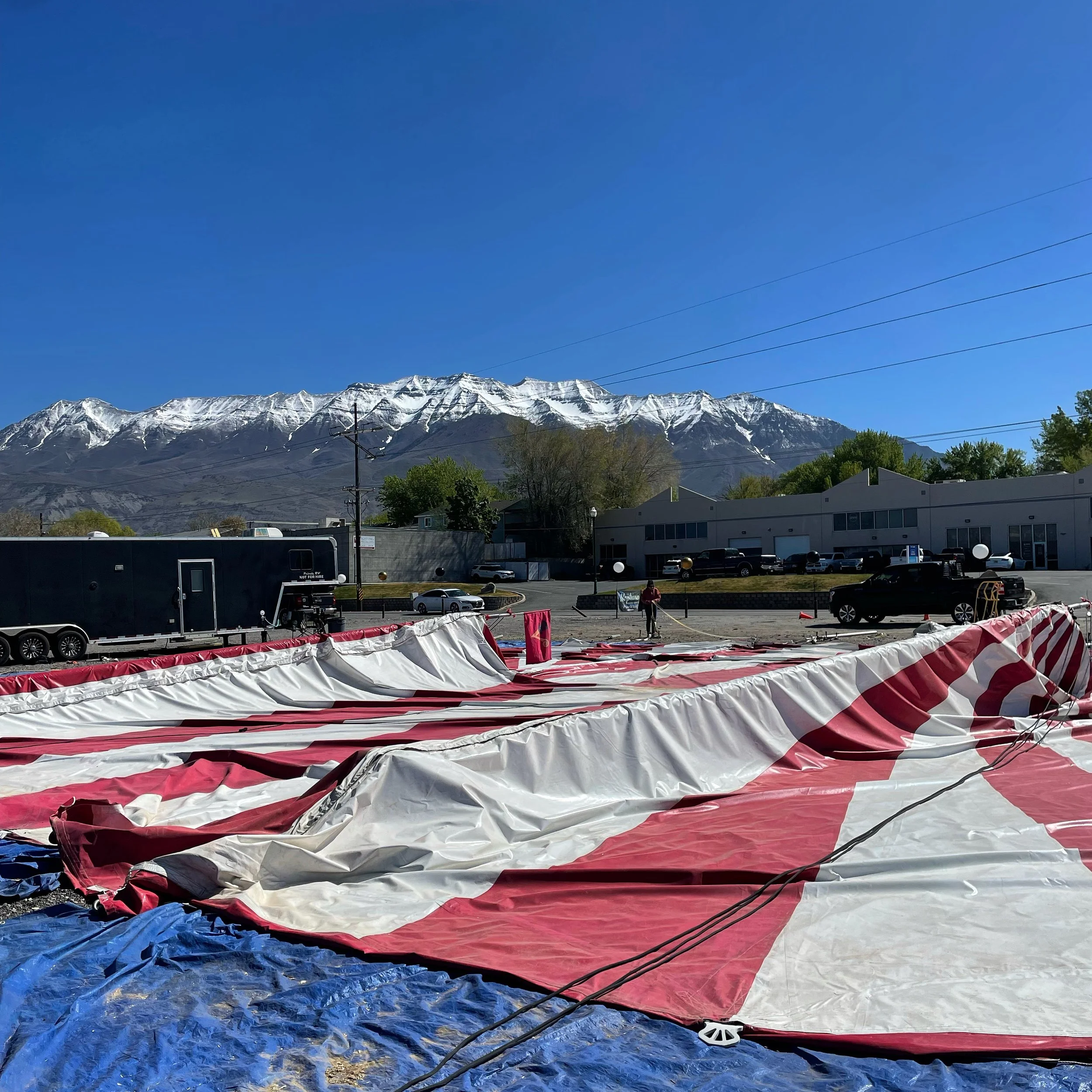 Torn red and white striped inflatable structure or banner on the ground with a mountainous landscape in the background under a clear blue sky.