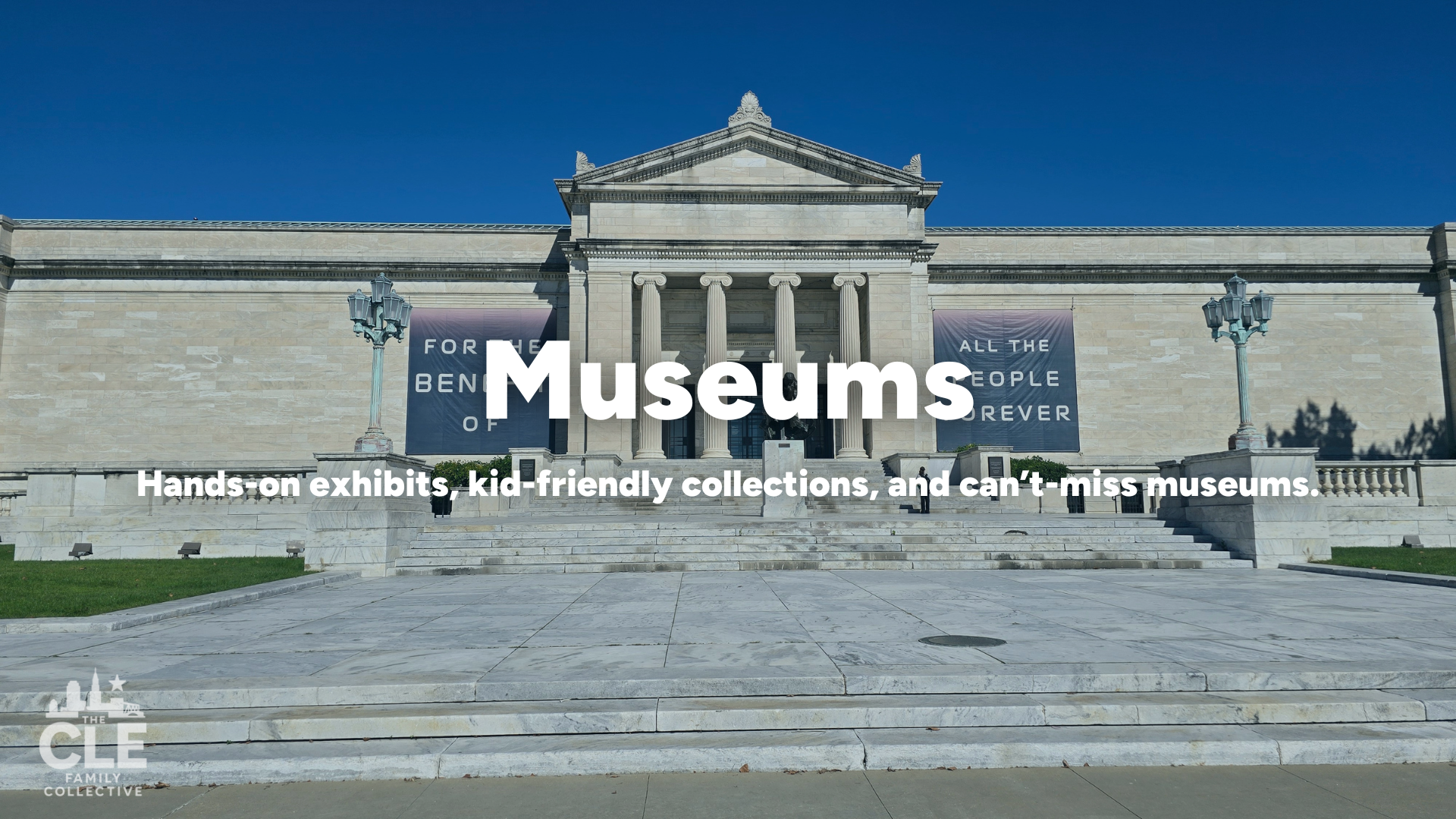 Front view of a museum building with steps leading up to columns, banners on either side, and a clear blue sky.