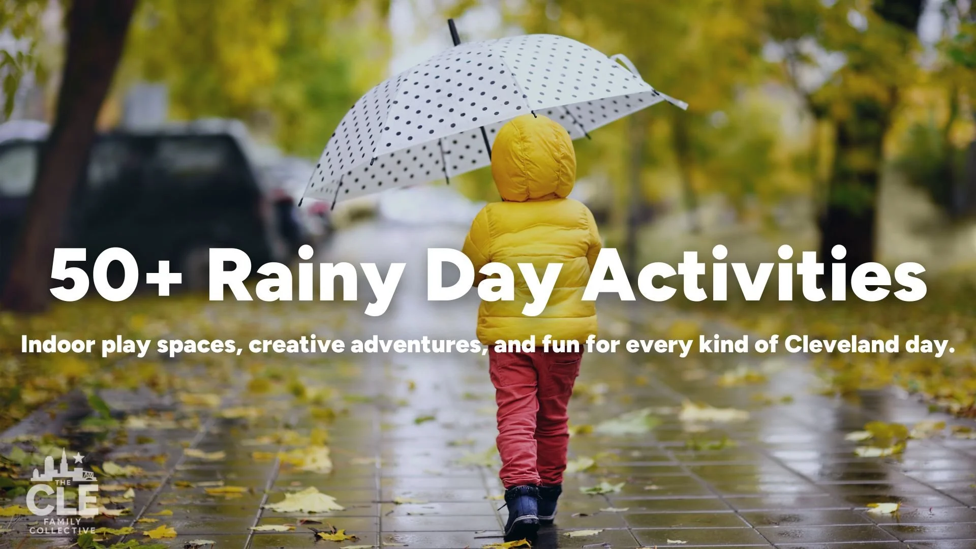 Child walking on rainy sidewalk with yellow jacket and polka dot umbrella, surrounded by autumn trees and wet leaves, promoting indoor rainy day activities.