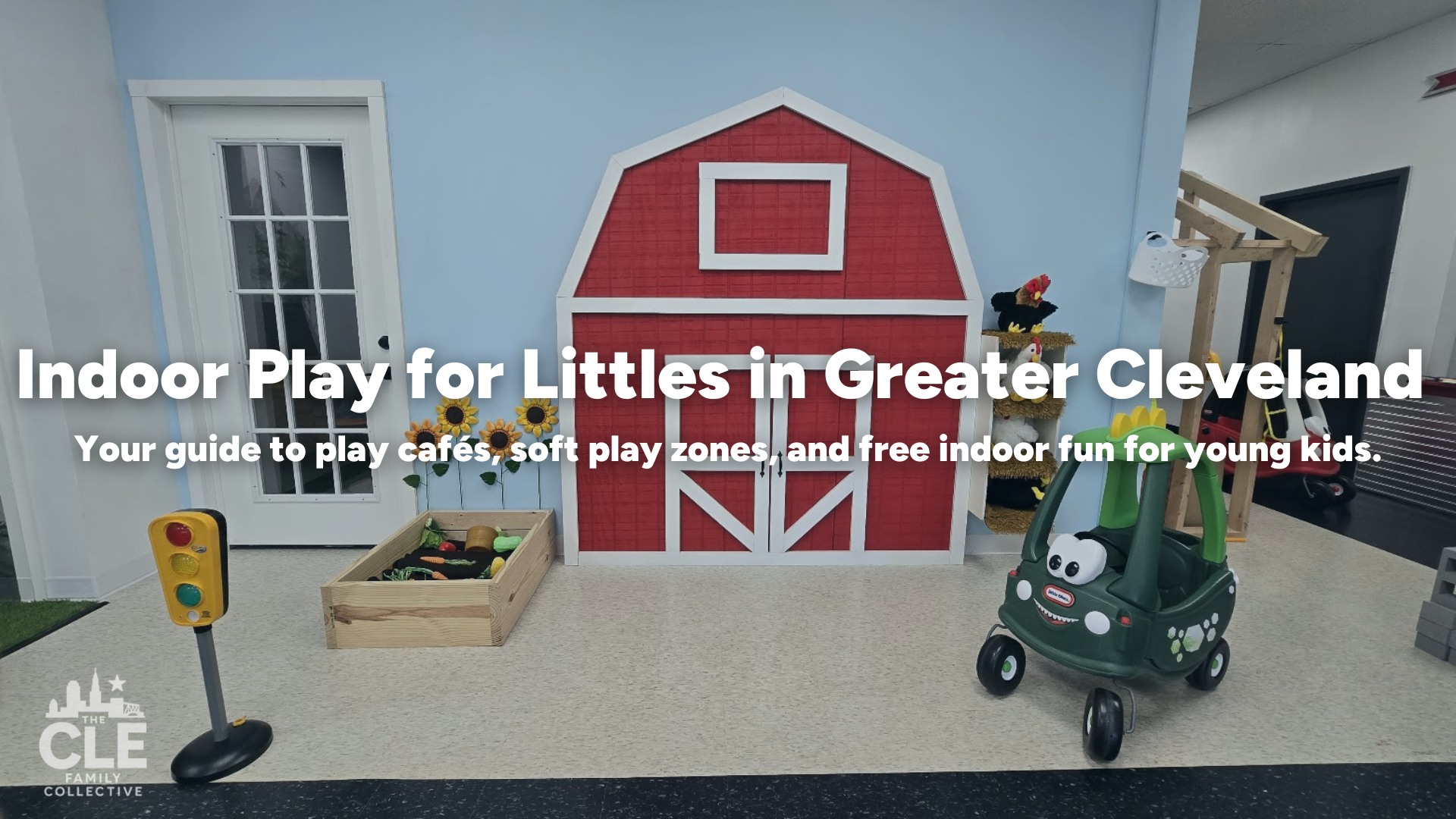 Indoor play area with a red barn background, a small wooden garden box with toys, sunflower decorations, a traffic light stand, a toy car with googly eyes, and various plush animals and toys, promoting indoor play for young children in Greater Cleveland.