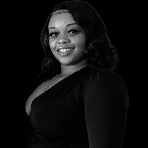 A smiling woman with dark shoulder-length hair in a black dress against a black background.
