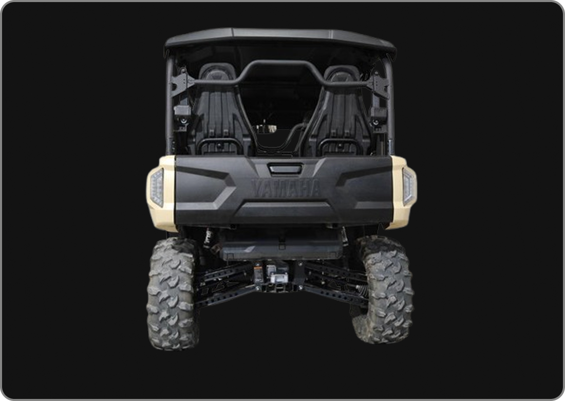 Front view of a black and beige off-road utility vehicle with large tires and a black interior, against a black background.