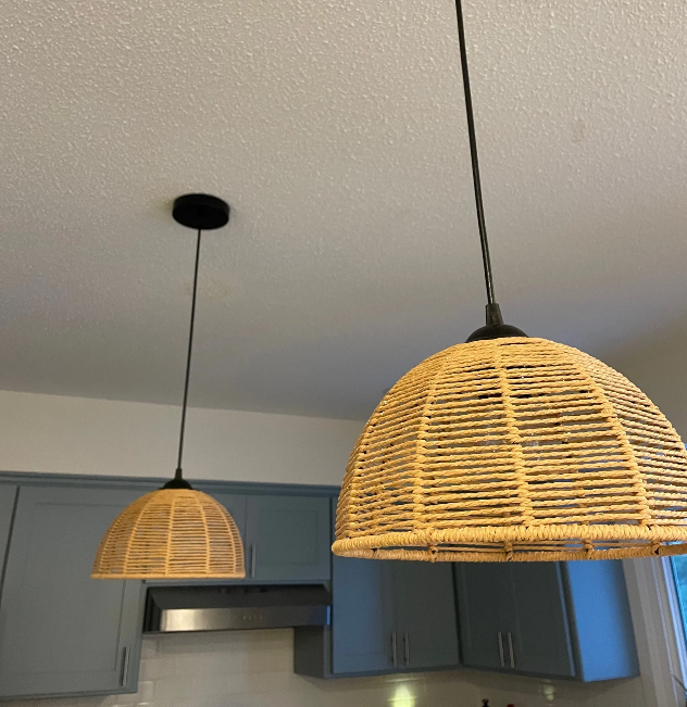 Two wicker pendant lights hanging from the ceiling above a kitchen counter with blue cabinets.