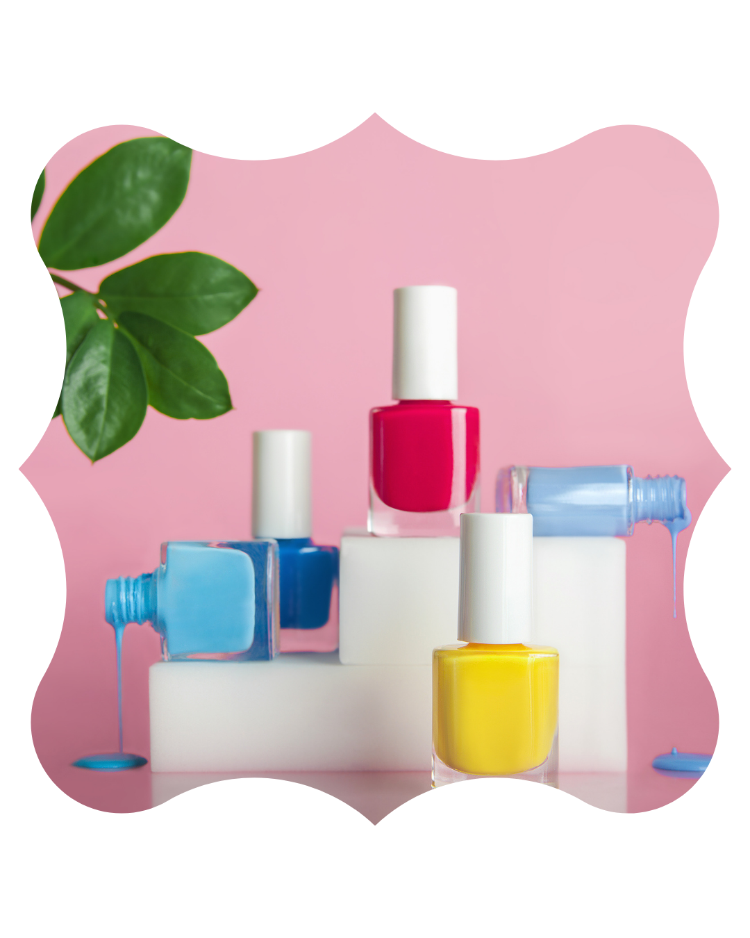 Colorful bottles of nail polish in red, blue, yellow, and light blue, with some spilling onto pink background, alongside green leaves in the upper left corner.