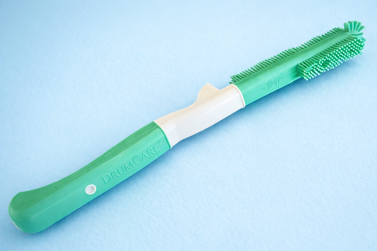 A green silicone baby bottle washer with a white middle section and a closed green handle, designed for cleaning baby bottles.