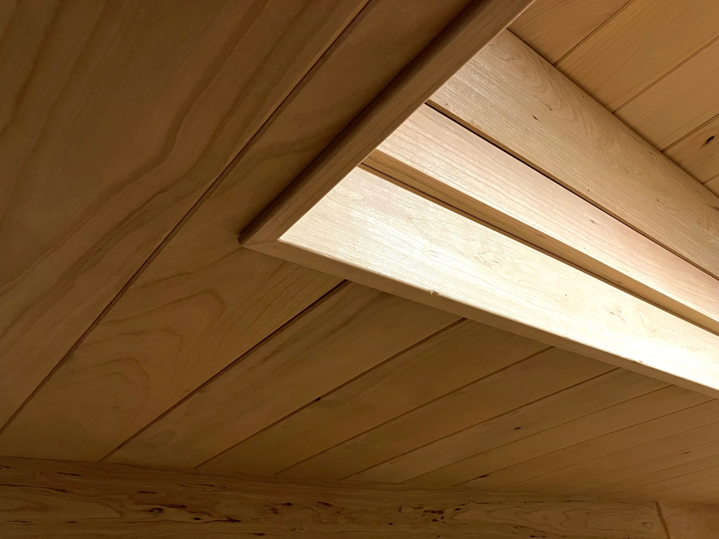 Close-up of a wooden ceiling with a skylight window.