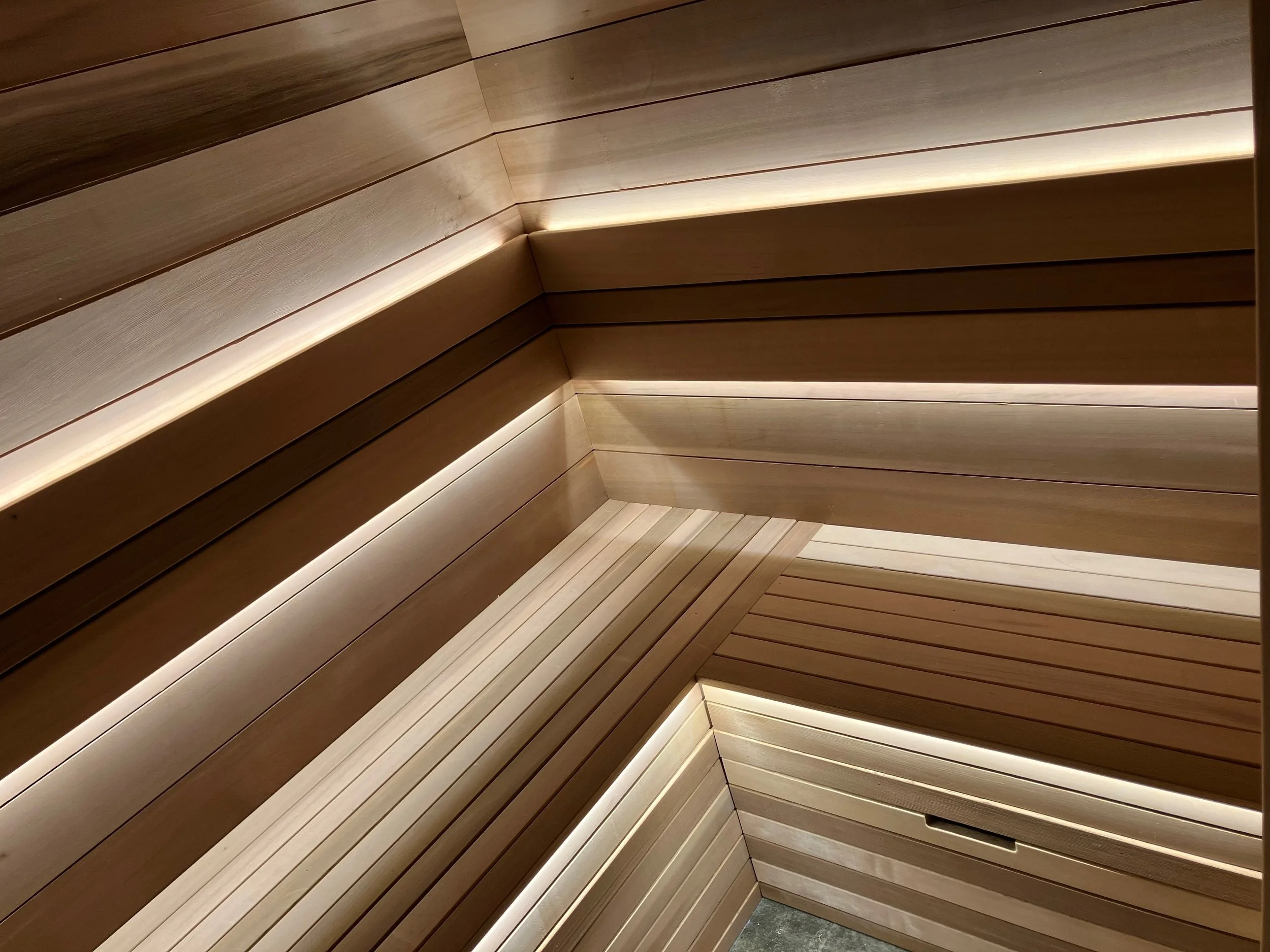 Interior view of a wooden sauna with tiered seating and soft lighting.