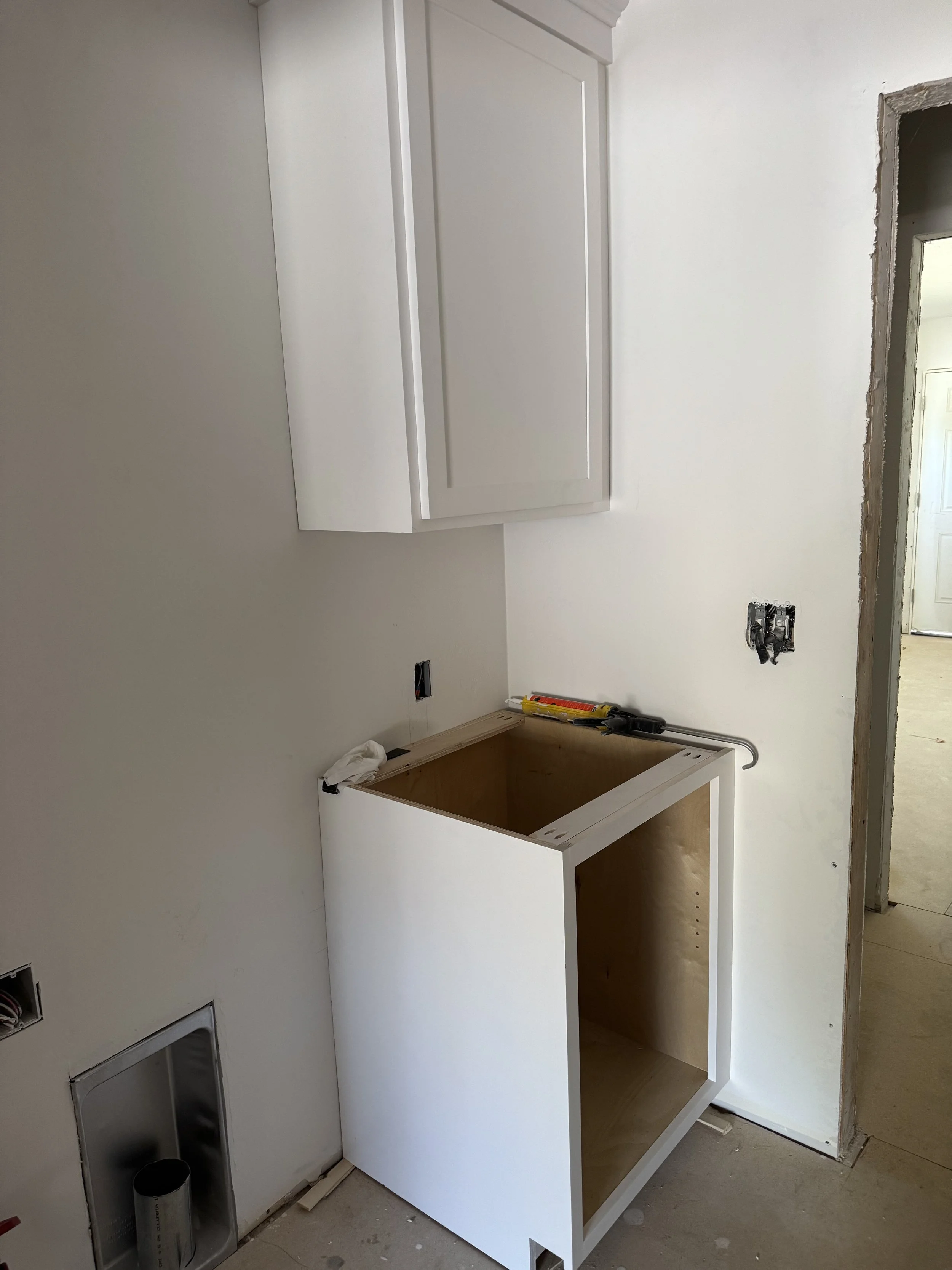 Kitchen cabinets and countertop installation in progress, with unfinished walls and construction tools visible.