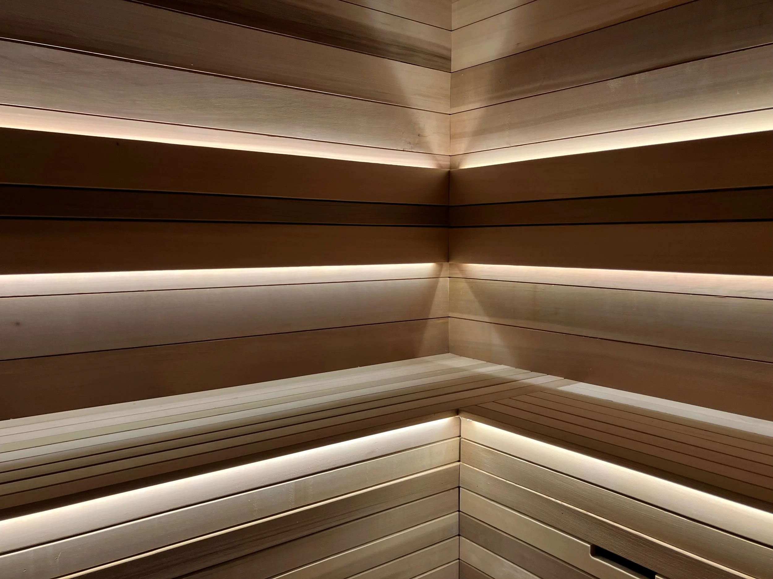 Inside a wooden sauna with horizontal wooden slats and LED lighting accents.