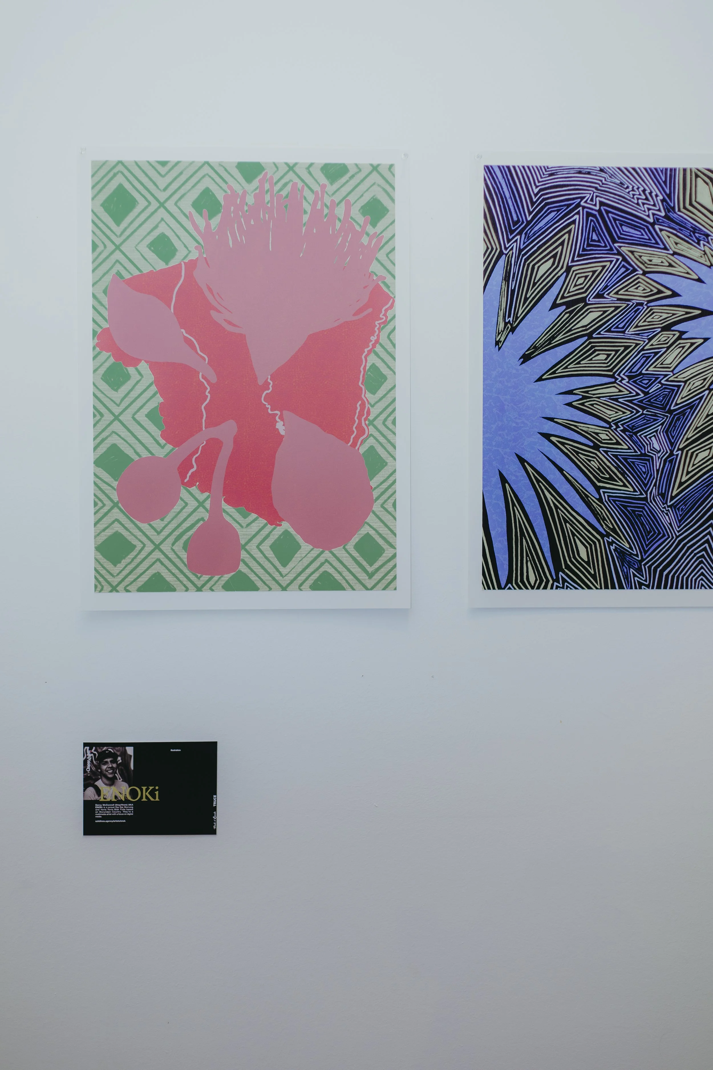 Two and three abstract posters hanging on a white wall, with a small black and white image with text below.