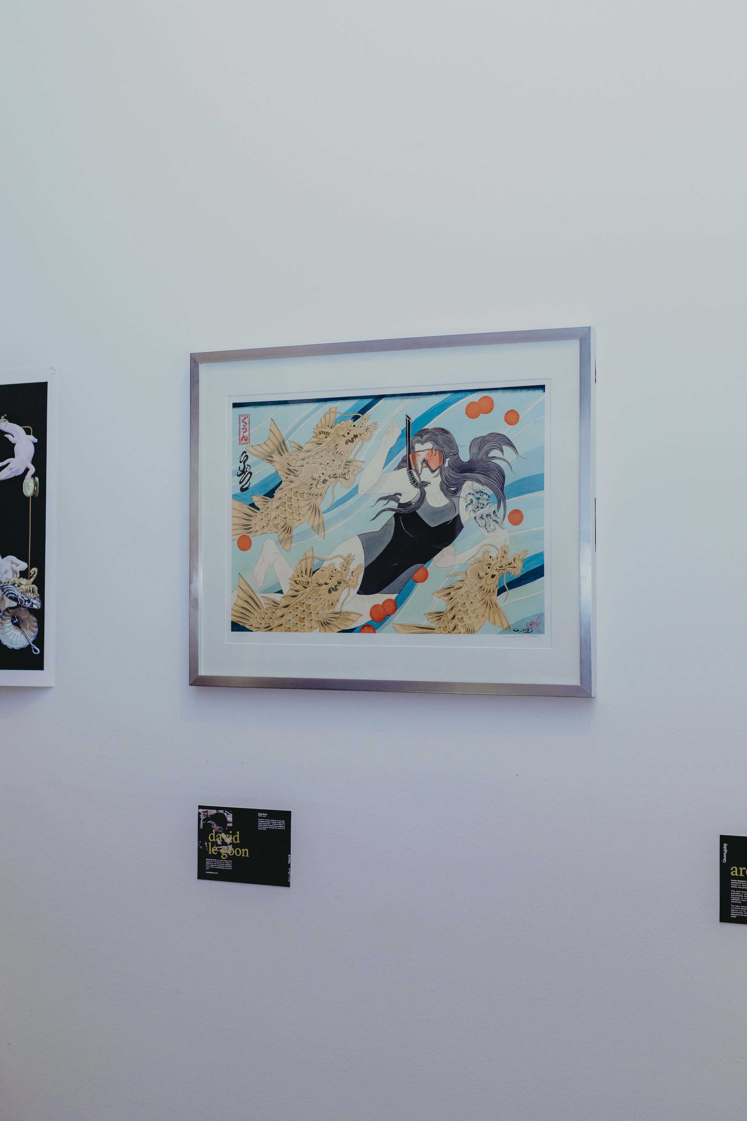 Art poster featuring a woman with long hair wearing snorkeling gear, surrounded by stylized golden fish and blue abstract waves on a white background.