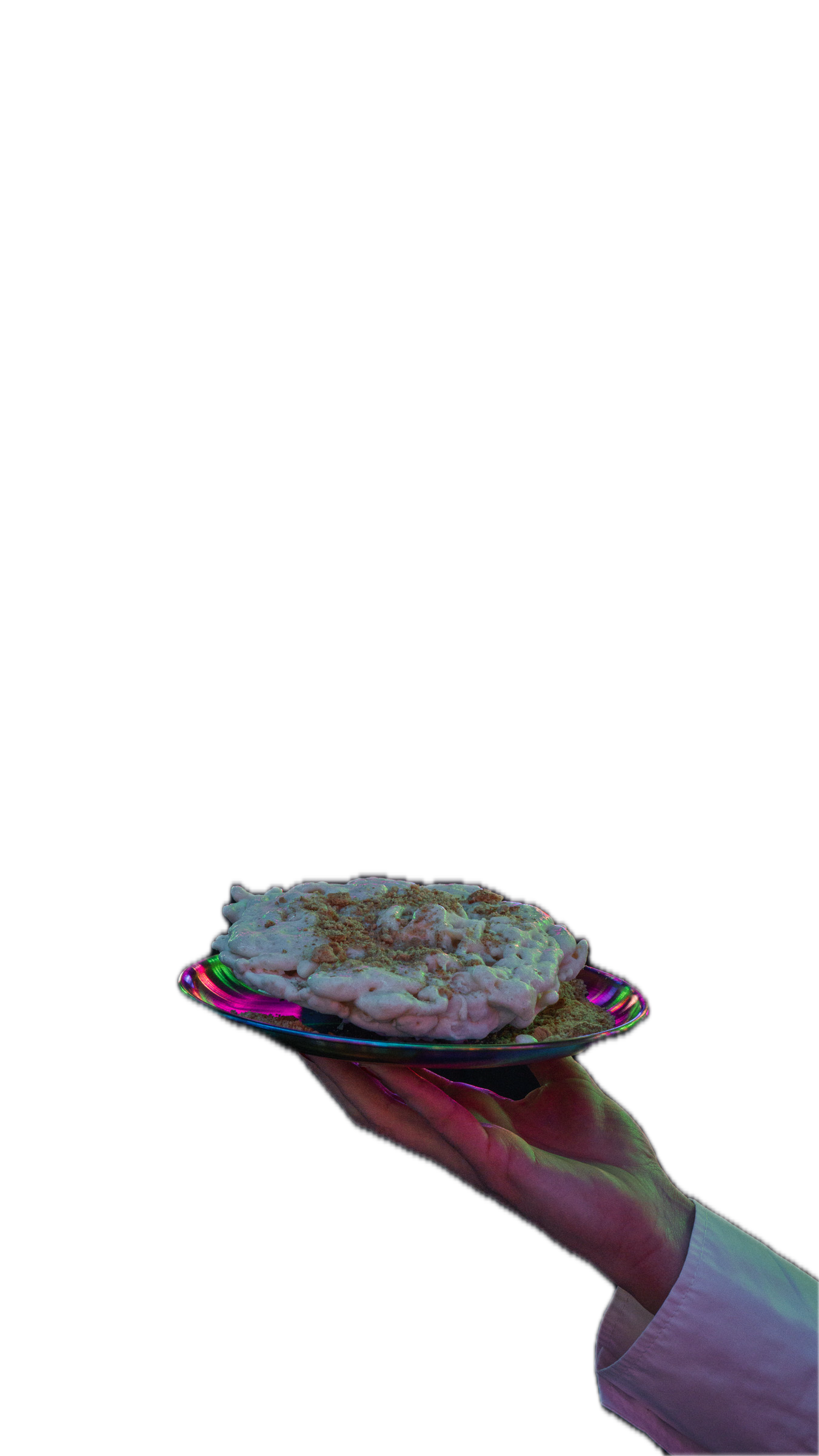 A hand holding a colorful plate with a scoop of ice cream topped with nuts against a black background.