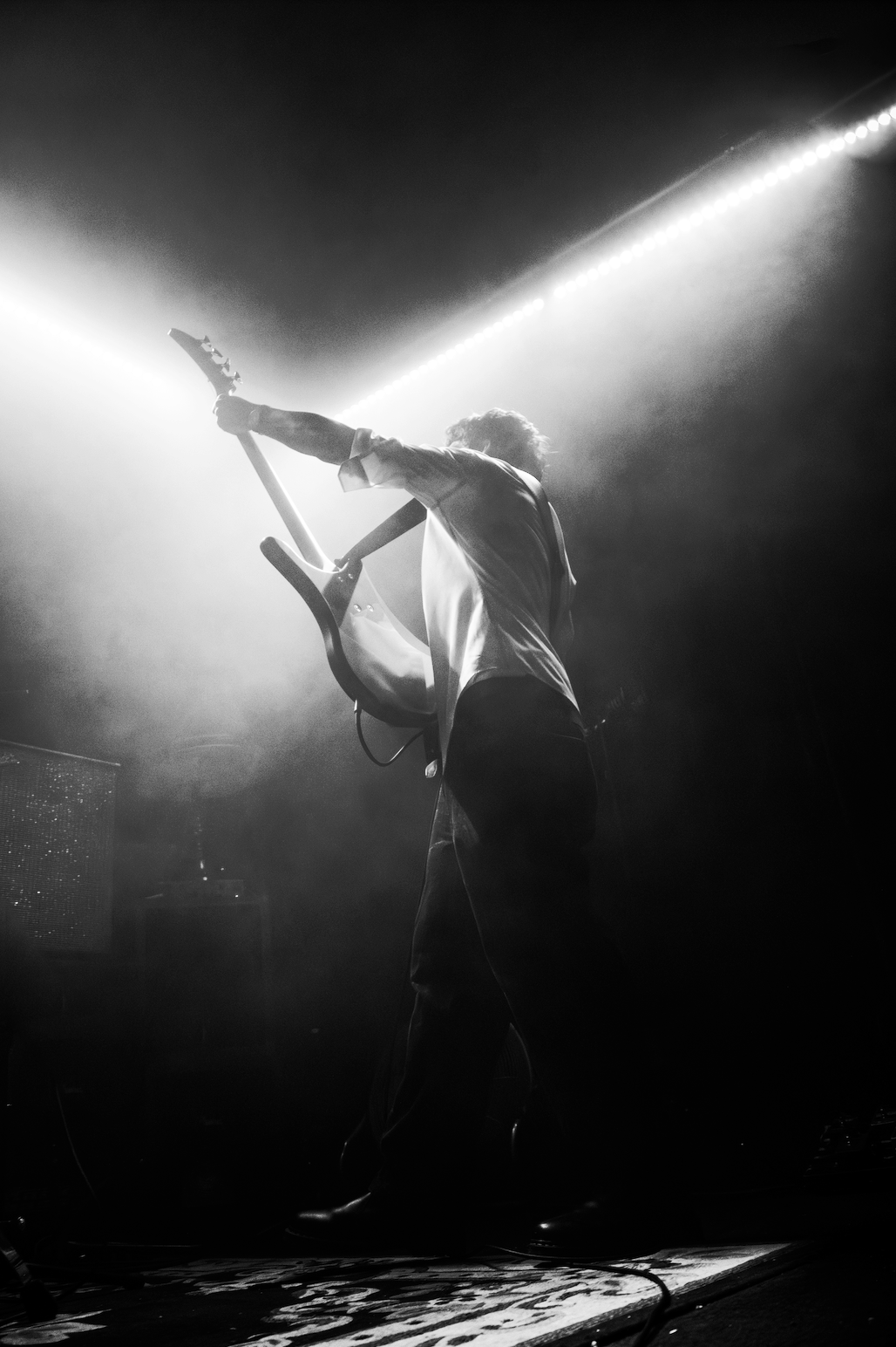 A person playing an electric guitar on stage with dramatic lighting and fog effects.