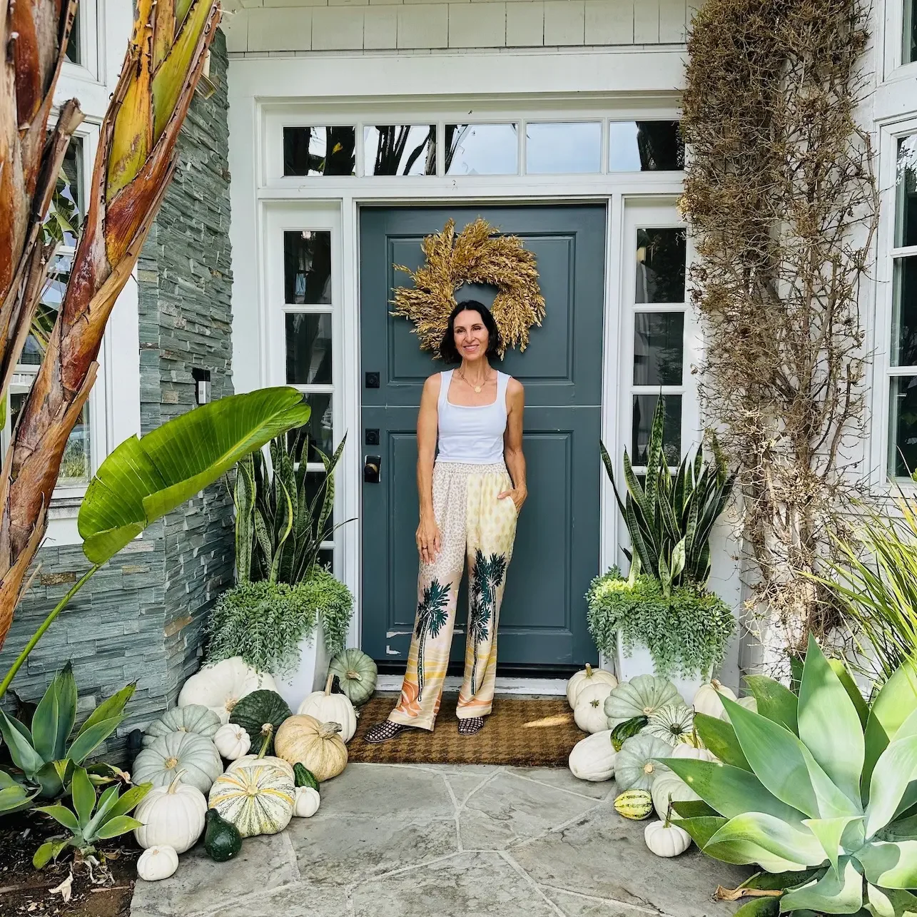 Client posing with completed blanc package porch design by Maison Pumpkin