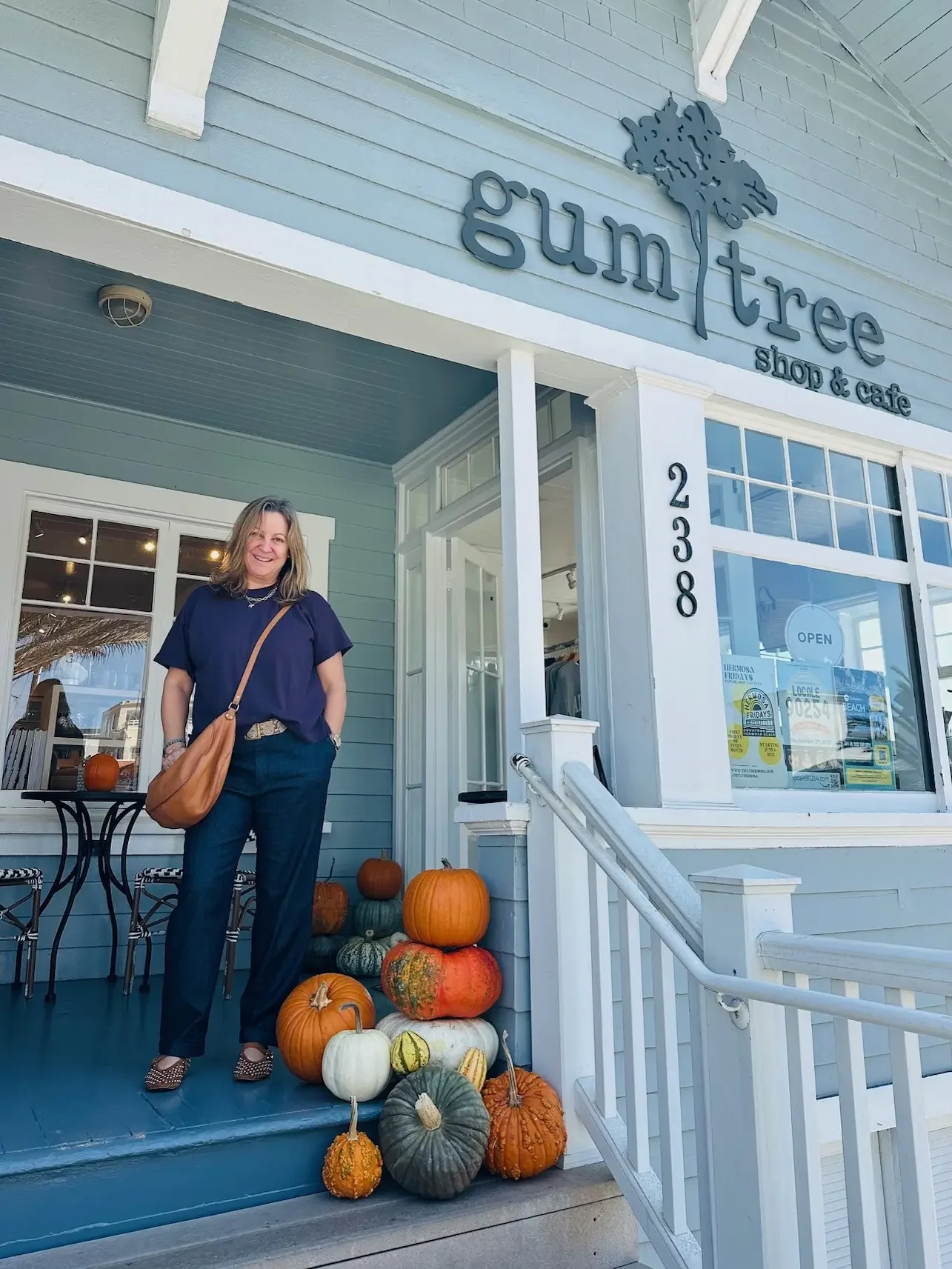 Client posing with completed autumn porch design by Maison Pumpkin
