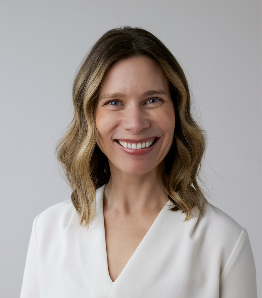 Man posing with checkered purple and blue collared shirt, short brown hair, beard and glasses smiling