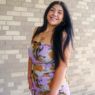 Woman posing in a colorful dress smiling at the camera with long brown hair