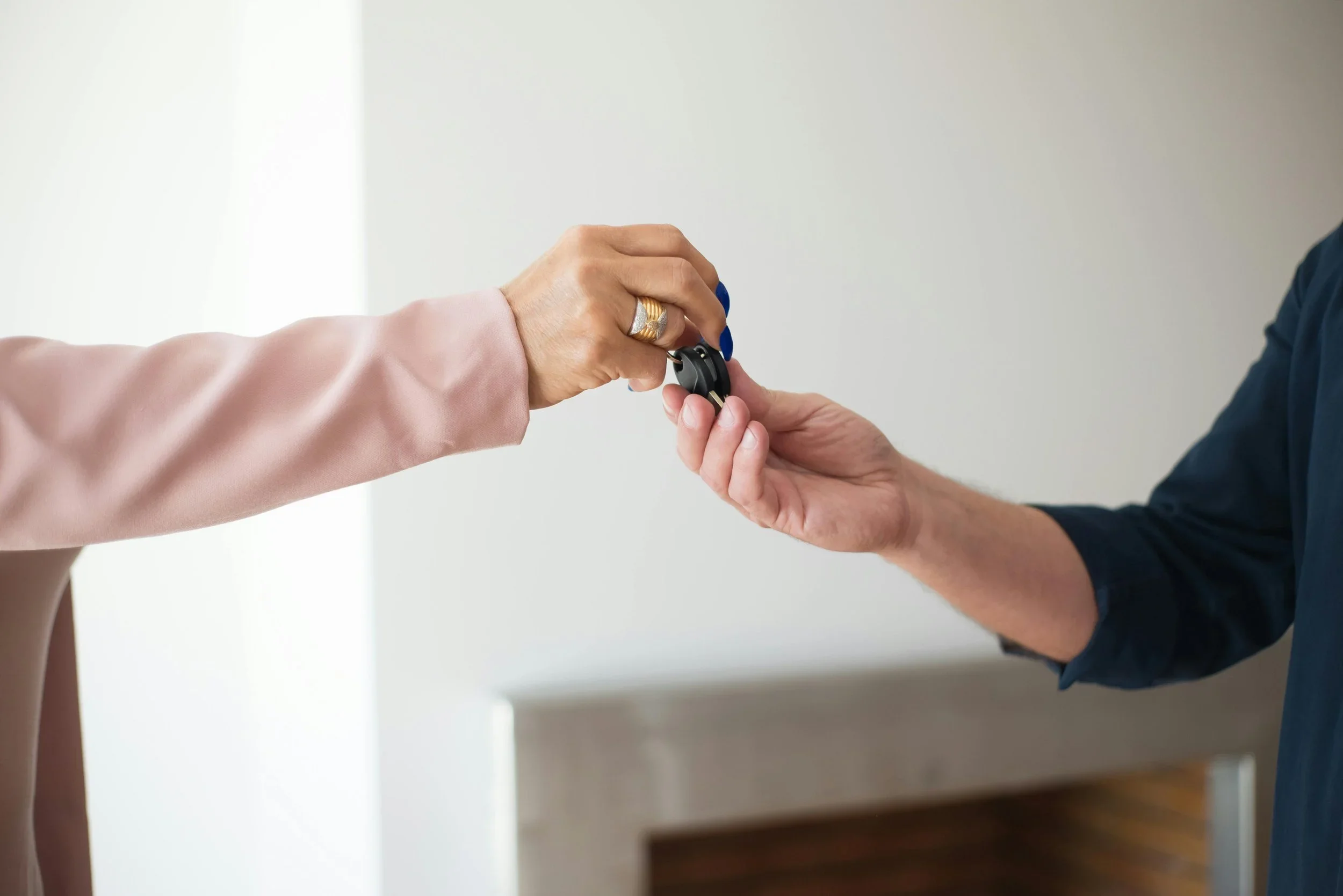 A woman handing a car key to a man in an indoor setting.