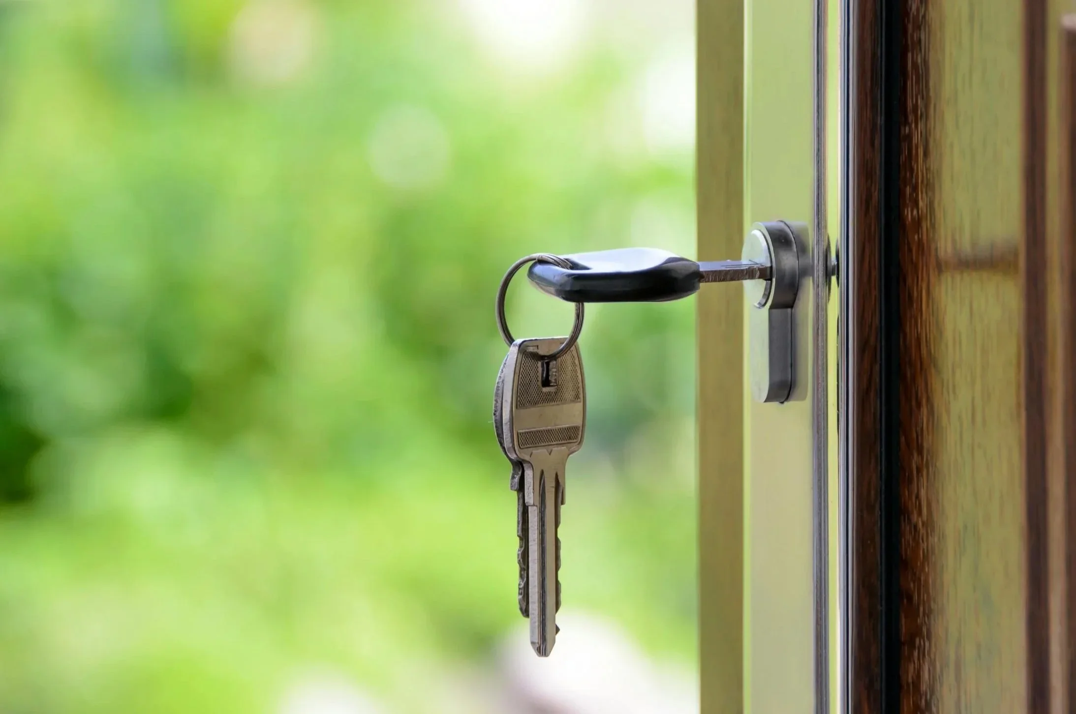 Key inserted in a keyhole on a door with a blurred green background.