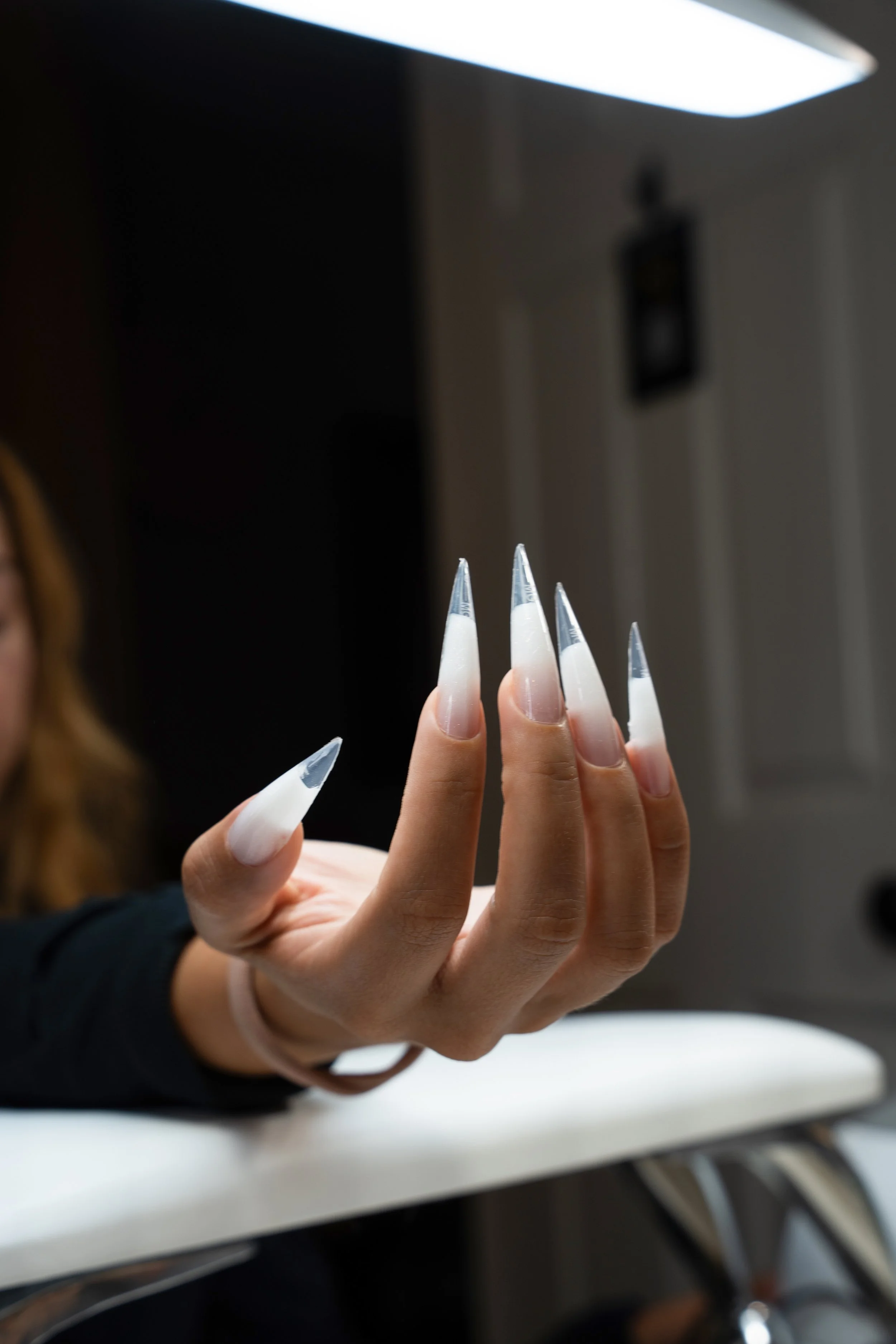 Close-up of a precision hard gel manicure with long white stiletto nails, at Maison d'Or.