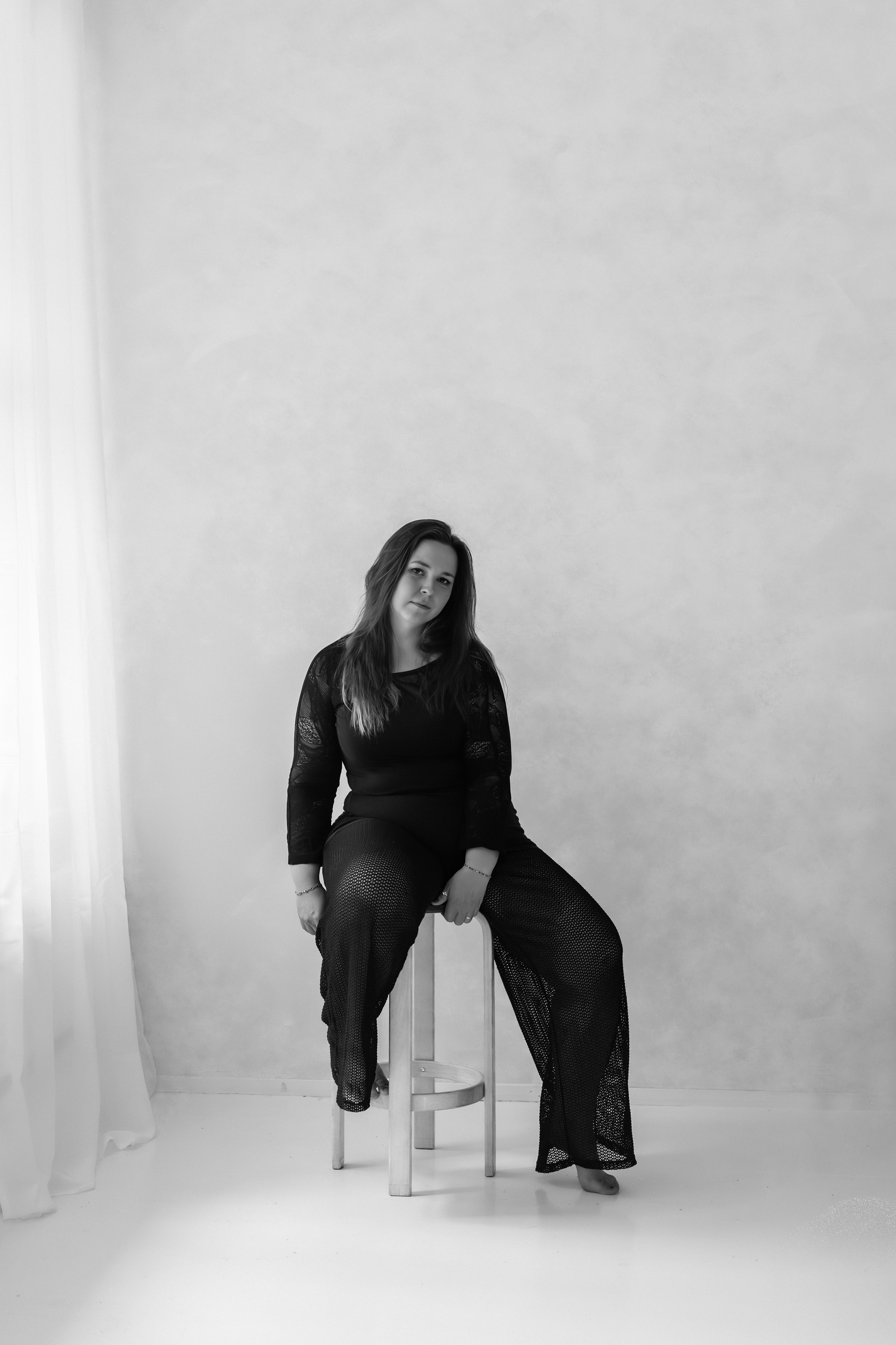 Henkilökuva nuoresta kauniista naisesta. Nainen istuu valokuvaaja Julia Karppisen studiossa Lahdessa. Mustavalkoinen kuva, jossa nainen katsoo kameraan.