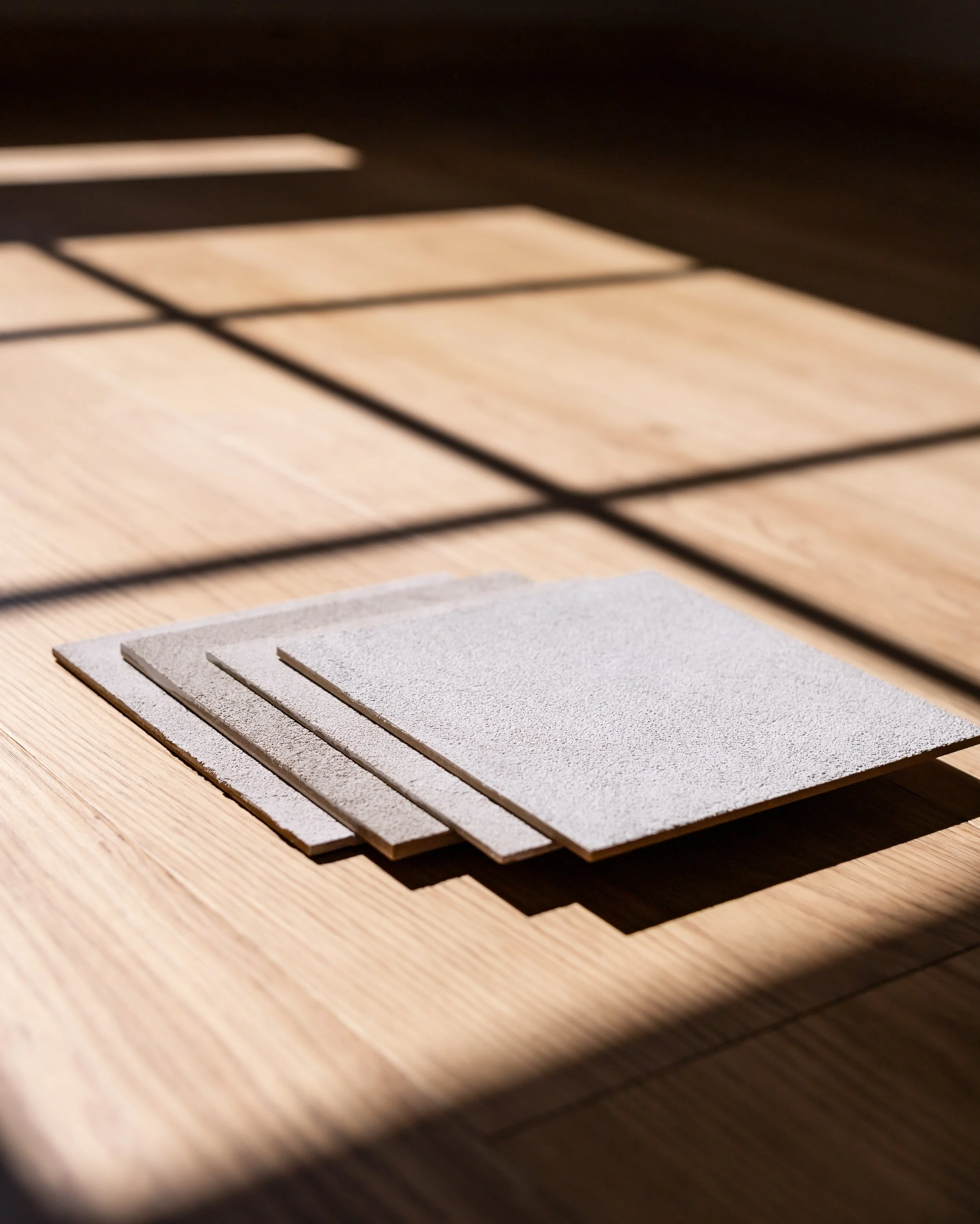 Kuva kolmesta seinälaastin värinäytepalasta  kauniissa valossa. Kuvassa tummat varjot ja pehmeä auringonvalo.