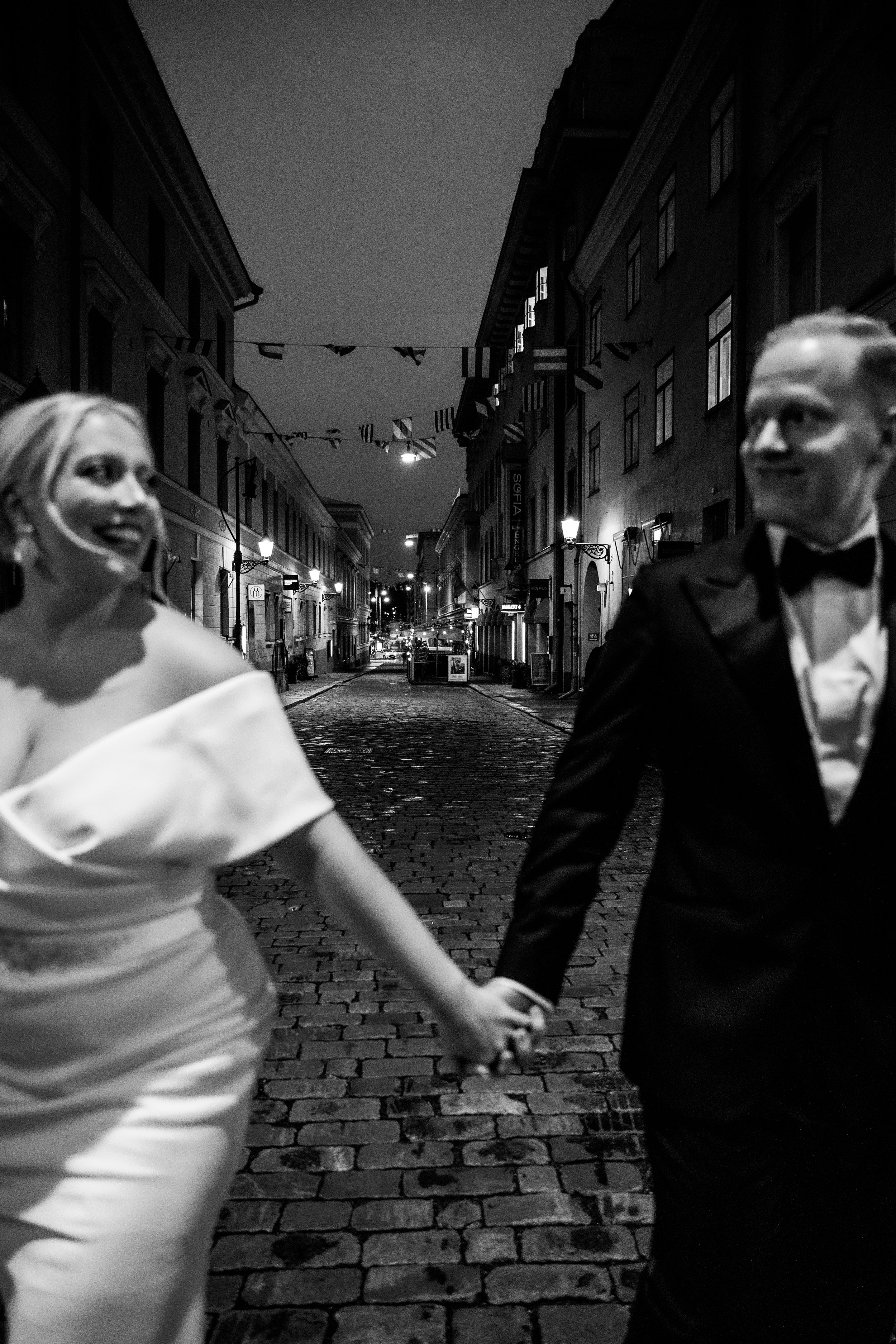 Morsian ja sulhanen juoksee käsi kädessä Helsingin kadulla.