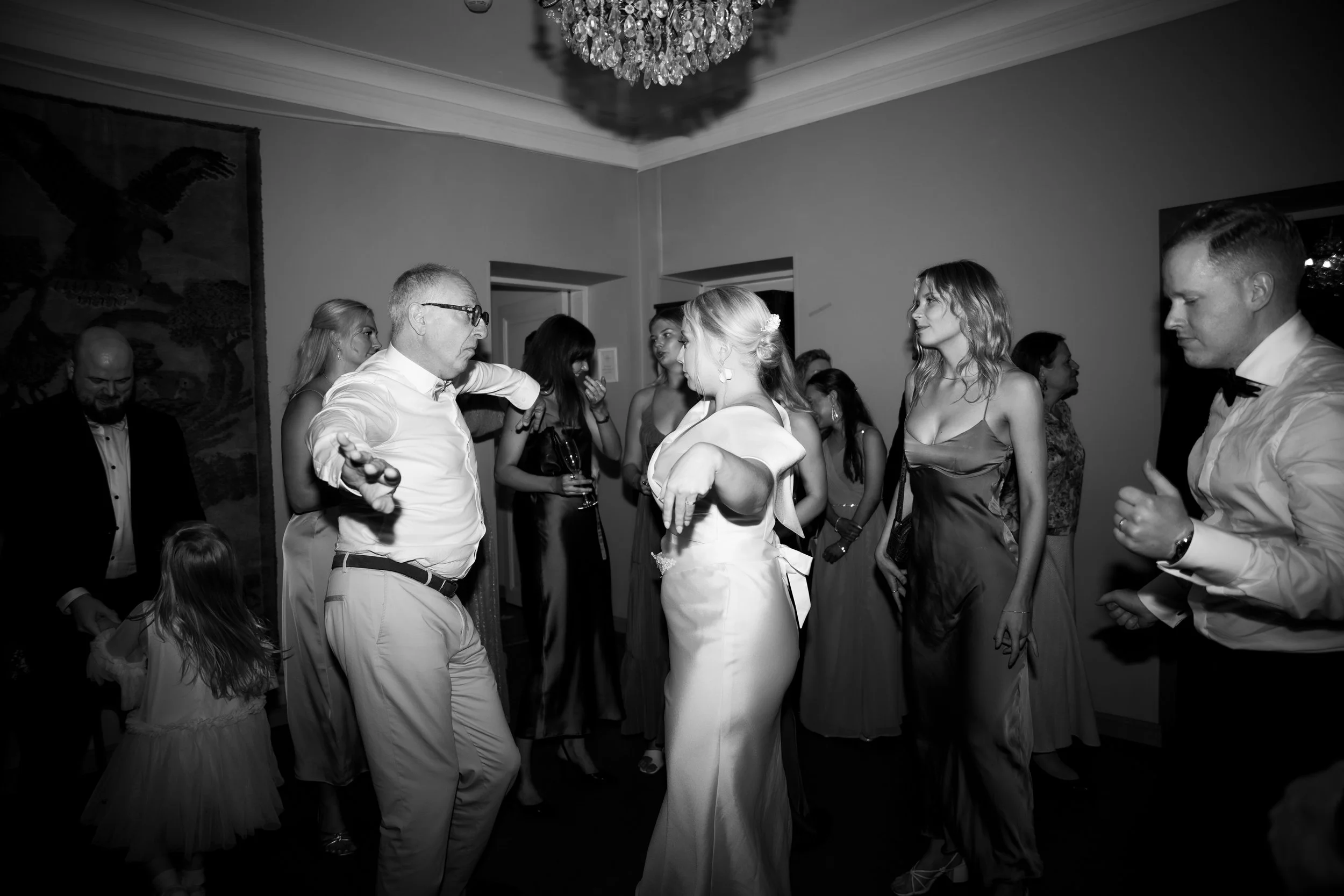 Häitä juhlittiin sisätiloissa, joissa tanssitaan ja seurustellaan. Tanssilattialla on useita ihmisiä, naisia ja miehiä, osa pukeutunut juhlavaatteisiin.