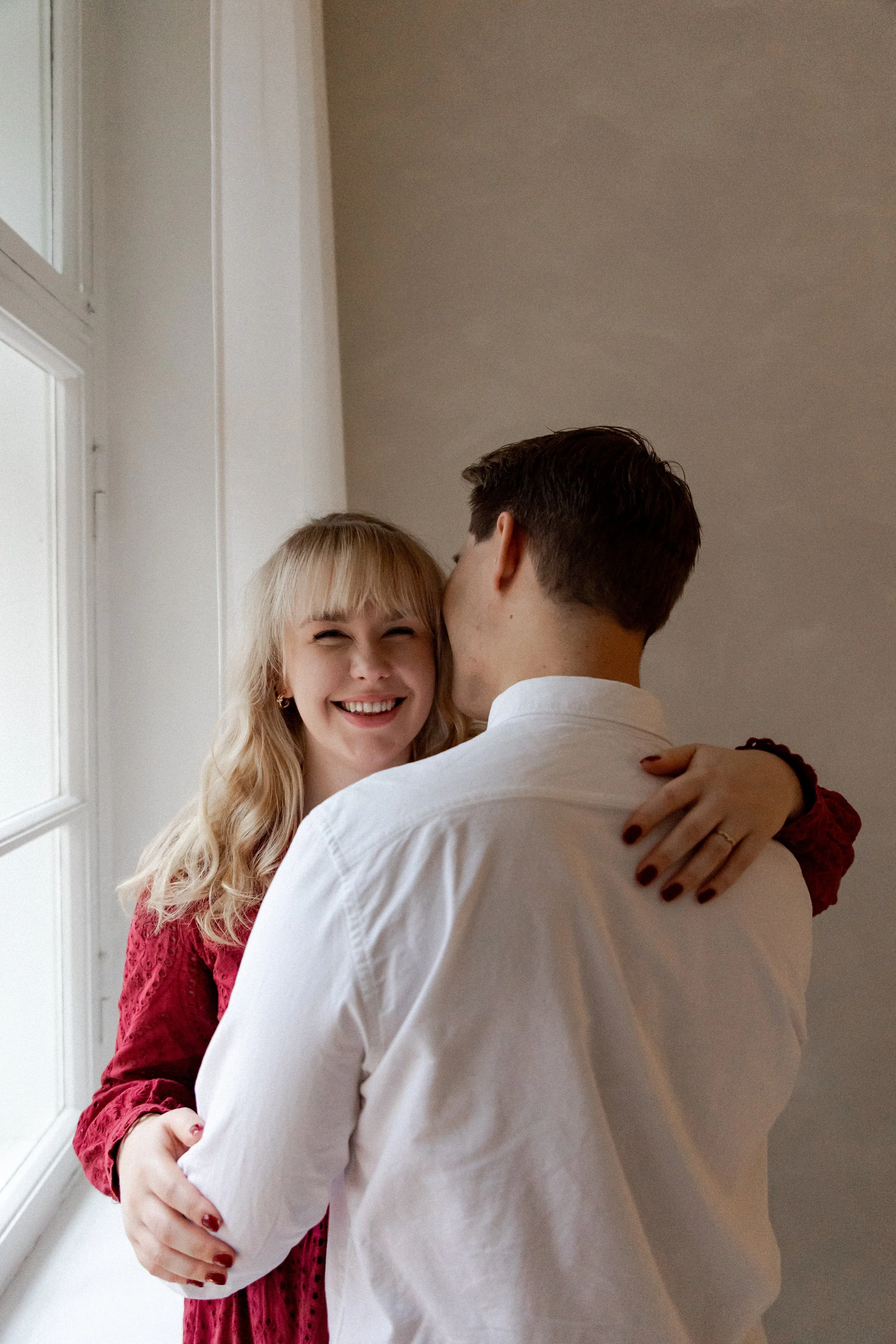 Söpö pariskunta halailee sisätiloissa, nainen hymyilee ja Kiristää miehen olkaa.