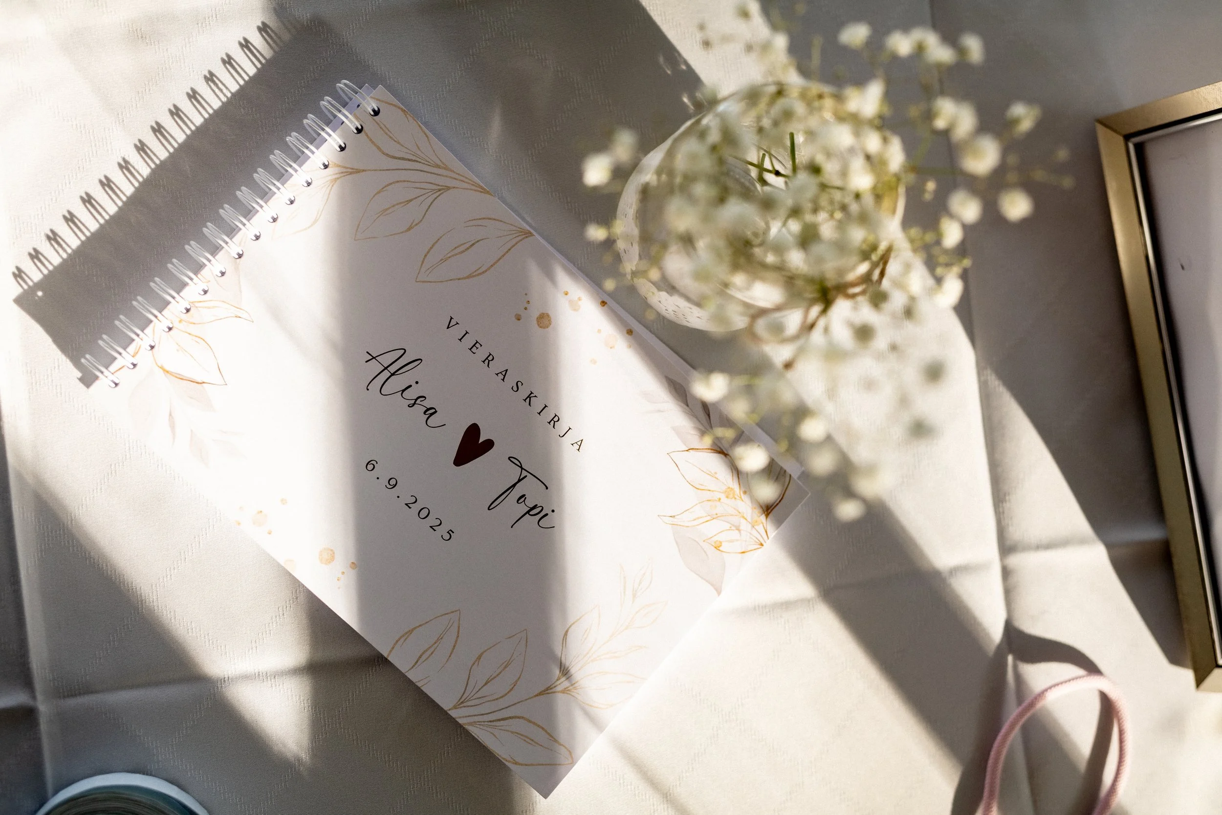 Viereksikirja ja kukkakimppu pöydällä. Hääpaikalta otettu kuva on kaunis ja hempeä. 