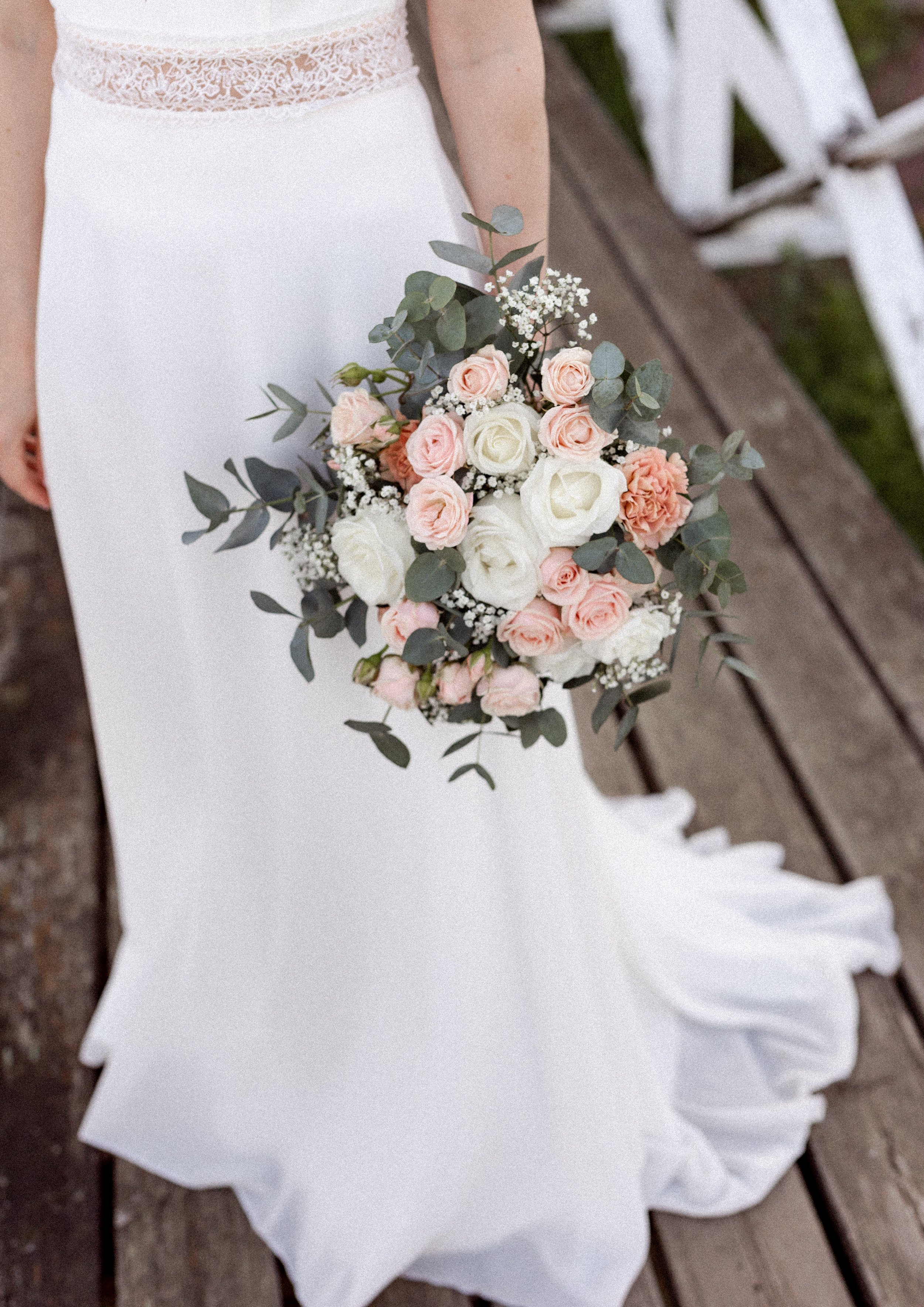 Kaunis hääpuku ja kimppu. Morsian pitää hääkimppua kädessään.