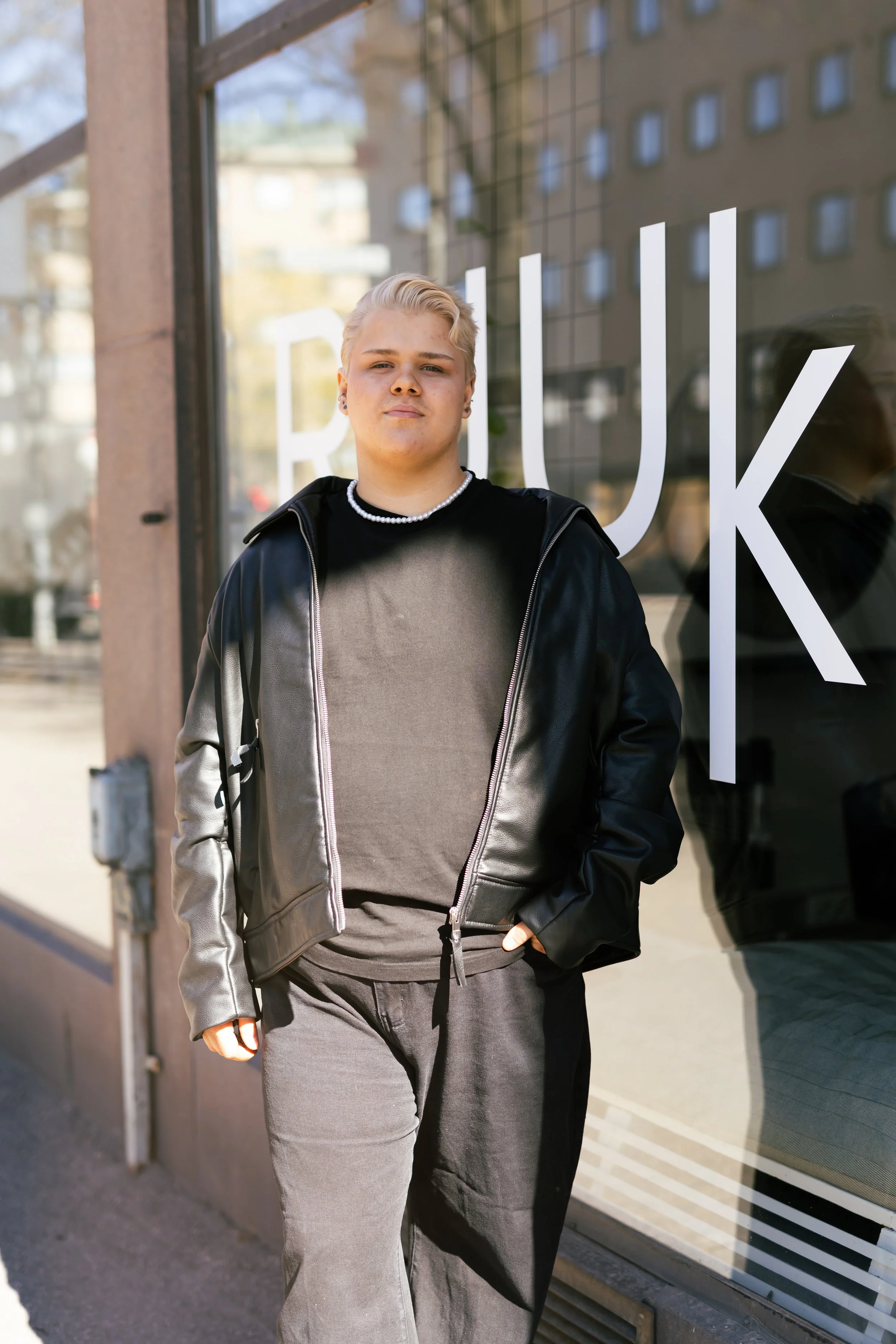 Nuori kampaamo omistaja seisoo liikkeensä edessä. 