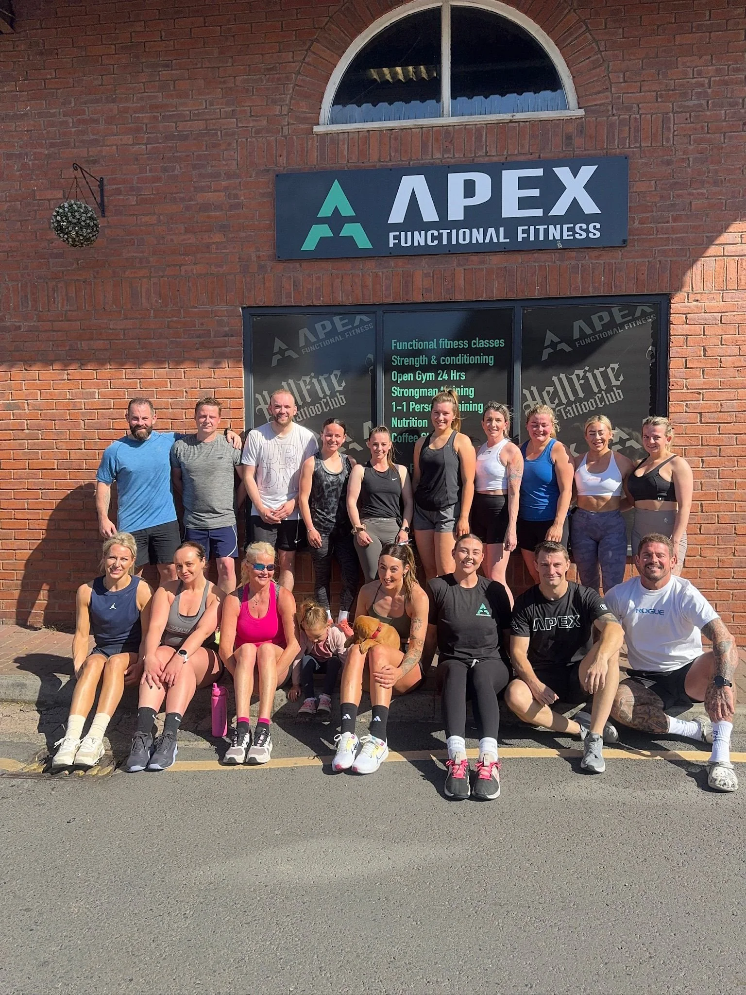 Group of people in athletic clothing gathered outside Apex Functional Fitness gym.