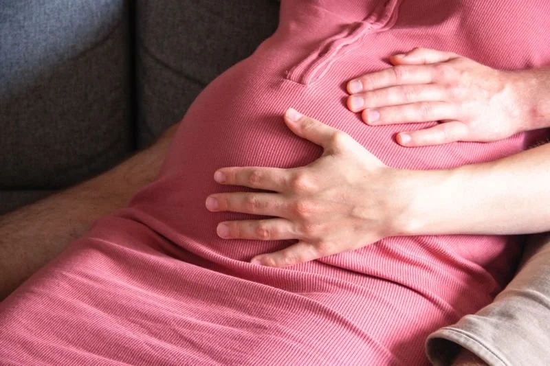 Liefdevolle handen op een zwangere buik, symbool voor de kracht van aanraking en verbinding bij shiatsu.