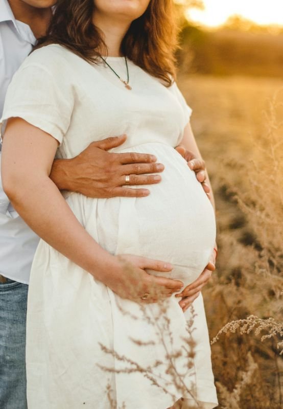 Zwangere vrouw bij zonsondergang, symbool voor rust en verbinding tijdens een babymoon.