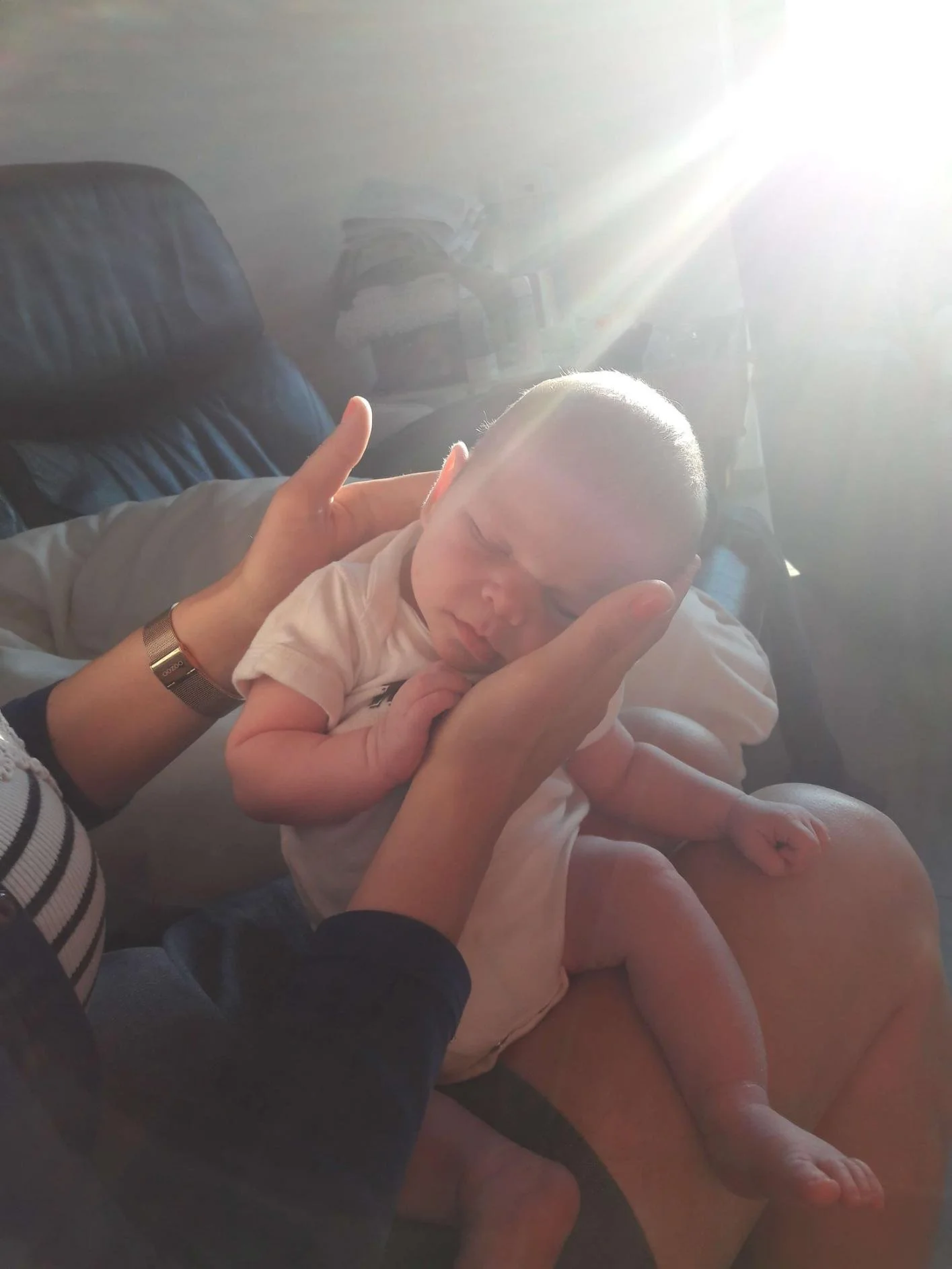 Een slapende baby in liefdevolle handen, symbool voor geborgenheid en cocoonen bij Bed en Baby.