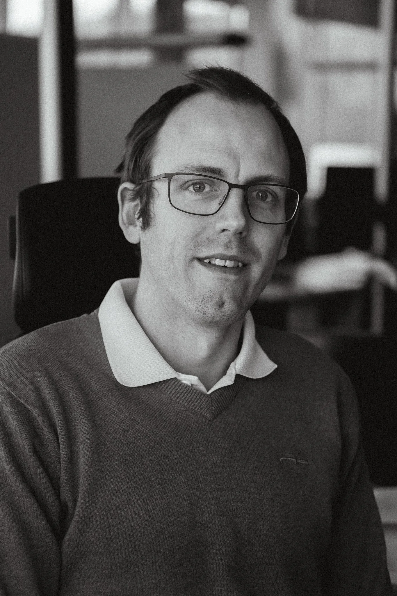 En man med glasögon, ler mot kameran.