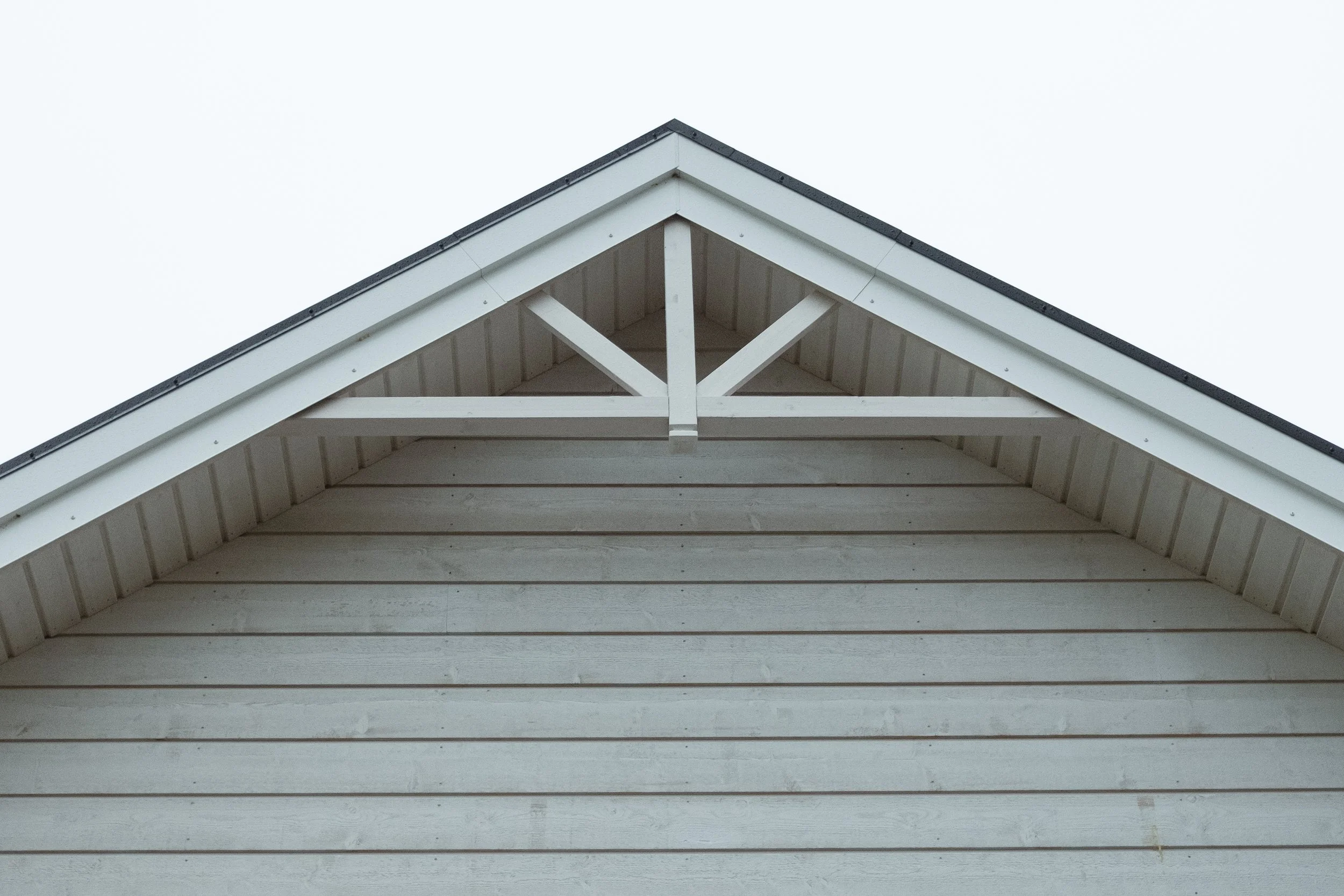 Närbild av takets spets på ett vitt trähus.