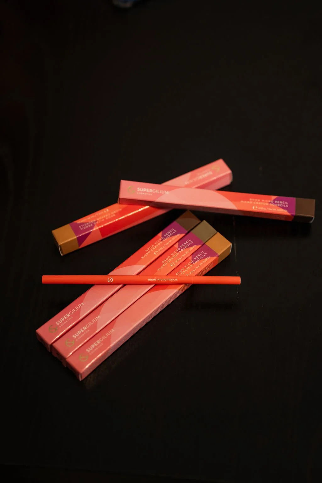 Verschillende verpakkingen van brow micro pennen en een losse micro pencil op een zwarte achtergrond. Beautysalon.