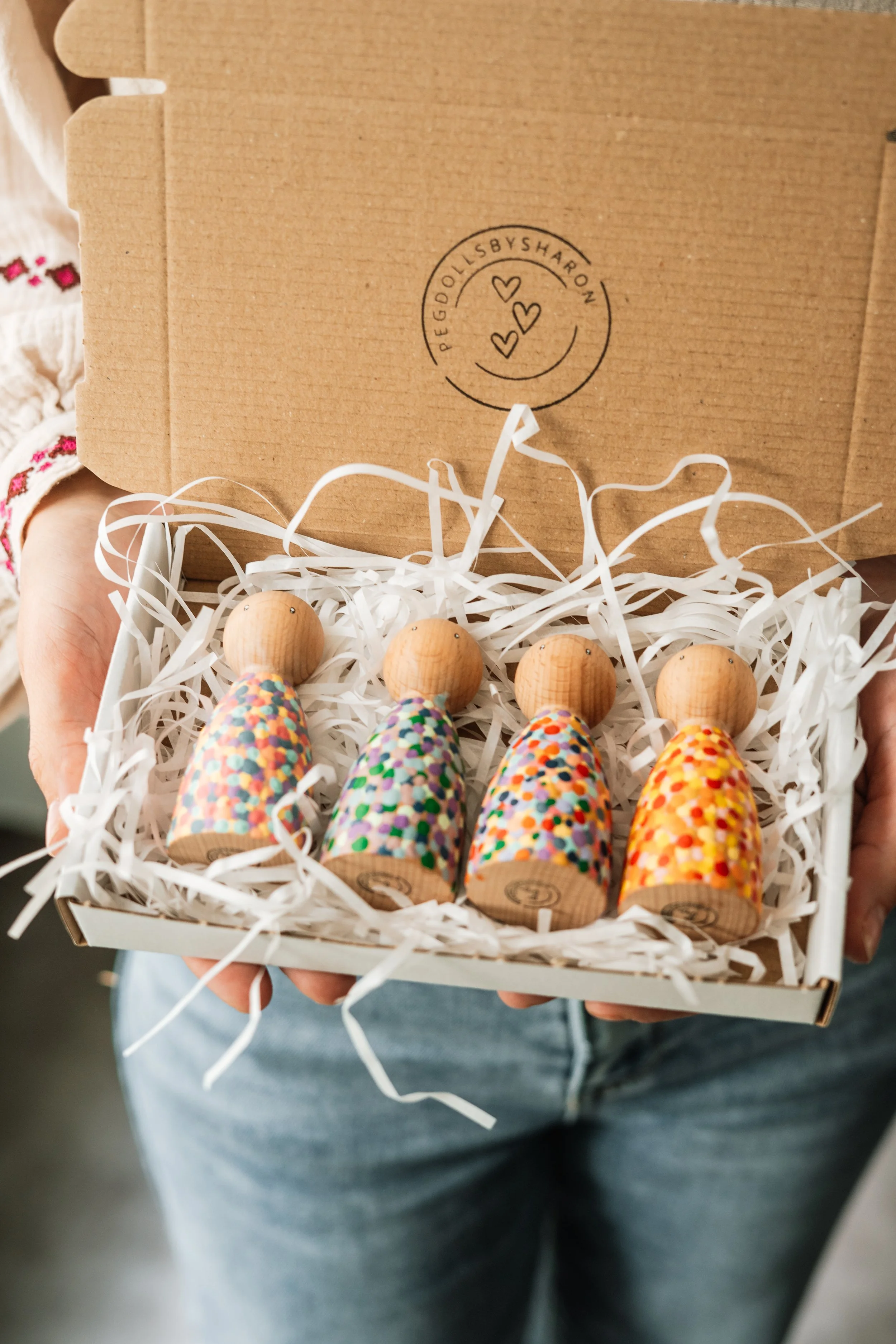 Set met vier houten varkentjes met gekleurde stippen en houten koppen, in een kartonnen doos met wit stro Packaging.