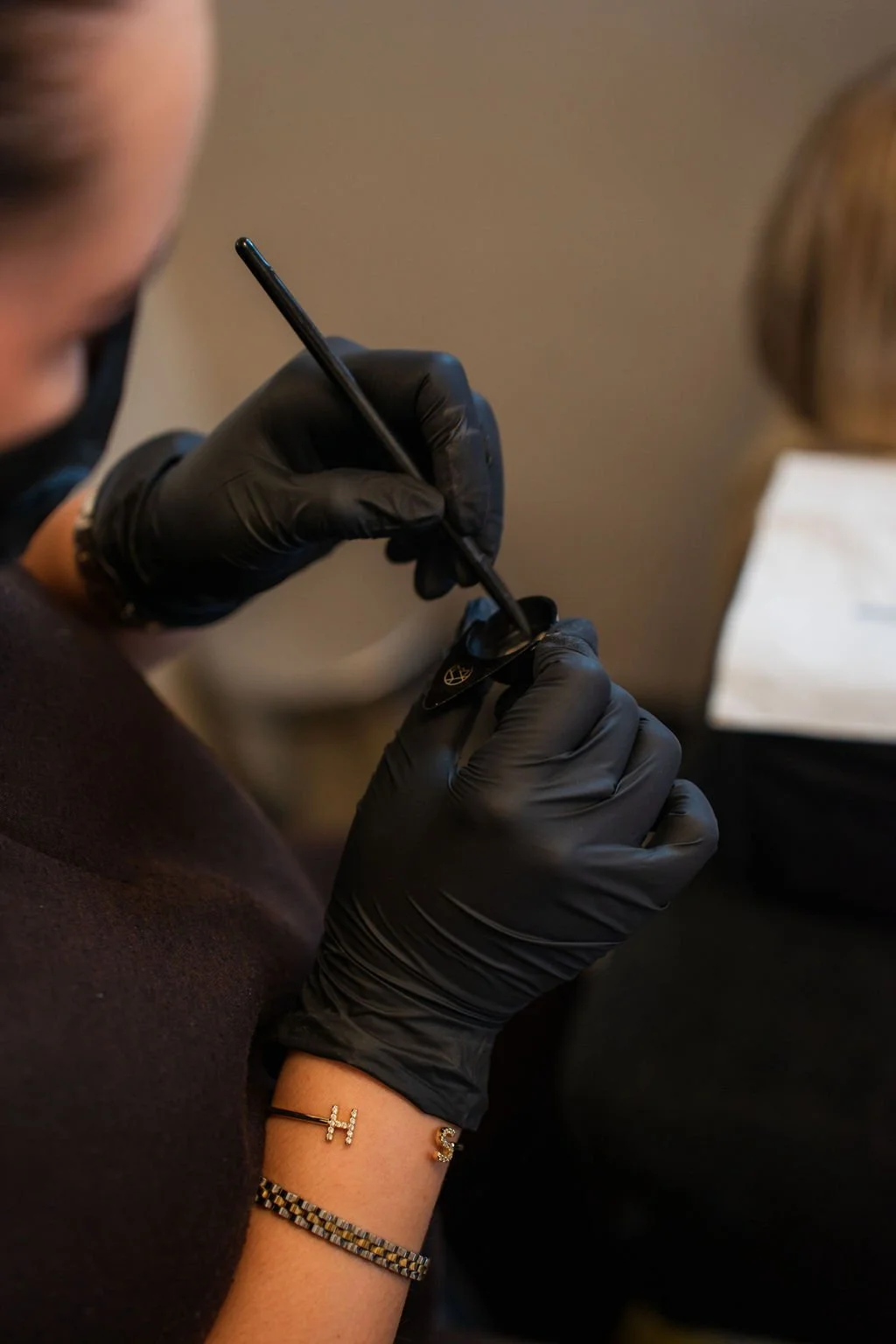 Een persoon die met zwarte handschoenen tatoeëert, het gebruik van een tatoeëernaald en inkt is zichtbaar.