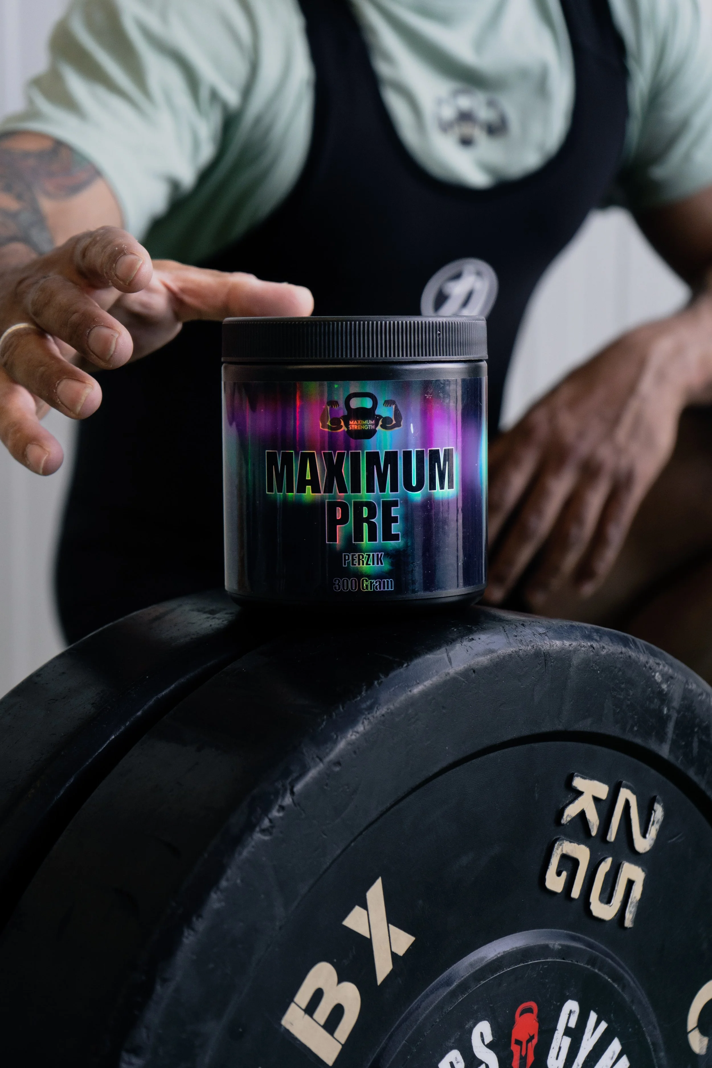 Een hand die een container met supplementen plaatst op een gewichtspunt in de sportschool. Sportsupplementen.