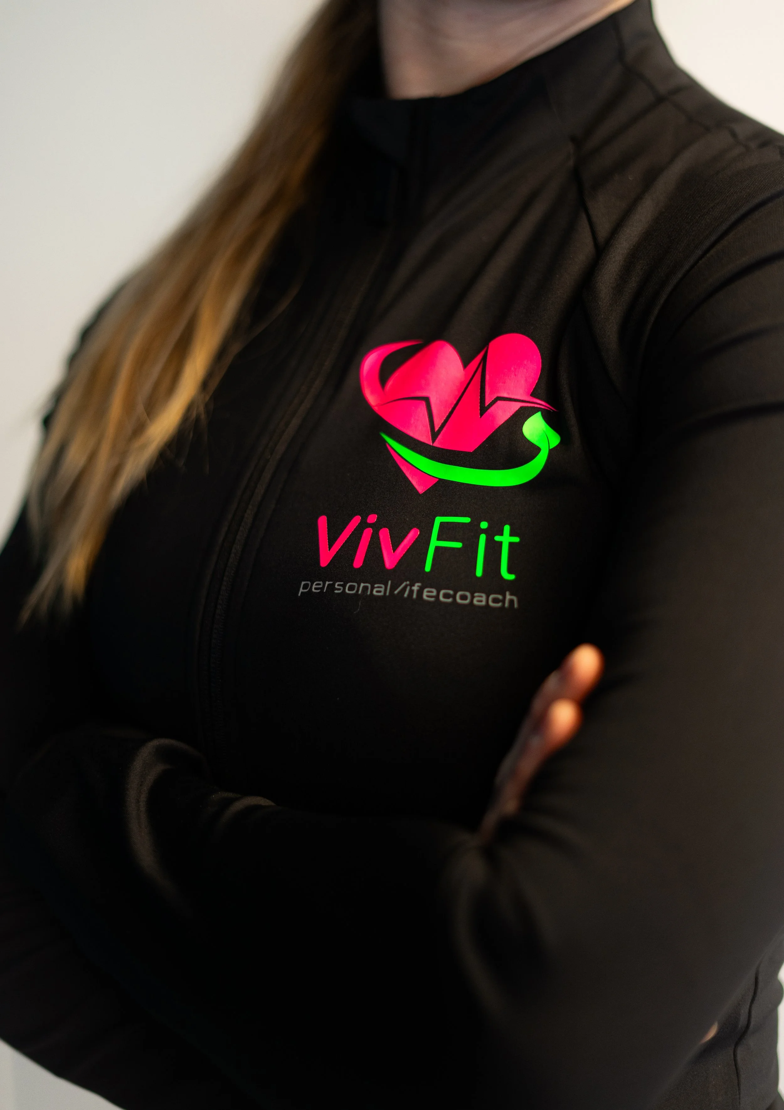 Persoon in zwart sportjack met logo en tekst "VIVFit personal / life coach".